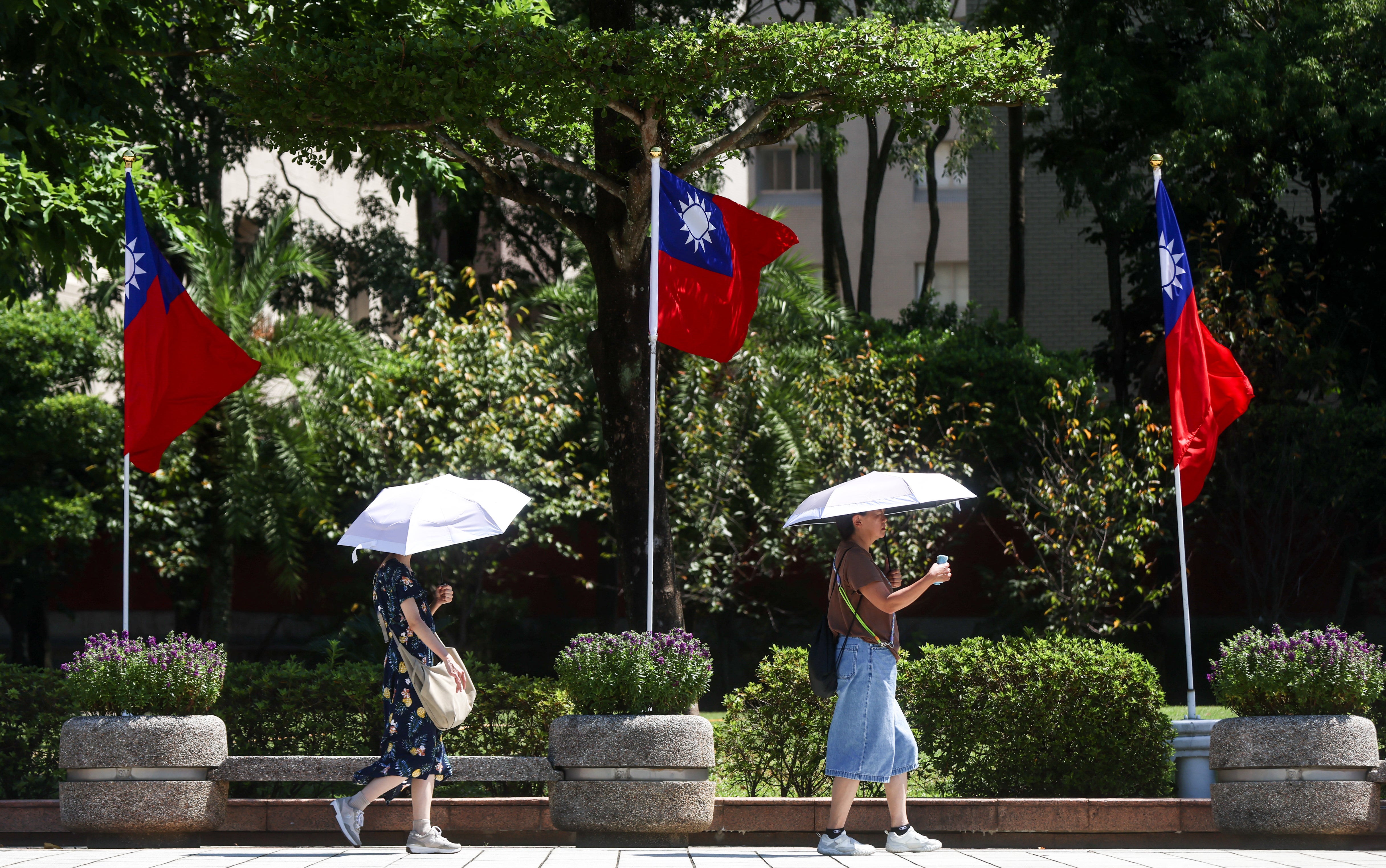 Visitors walk with umbrellas past Taiwanese national flags at the National Revolutionary Martyrs' Shrine in Taipei on September 23, 2026 (AFP/Getty)