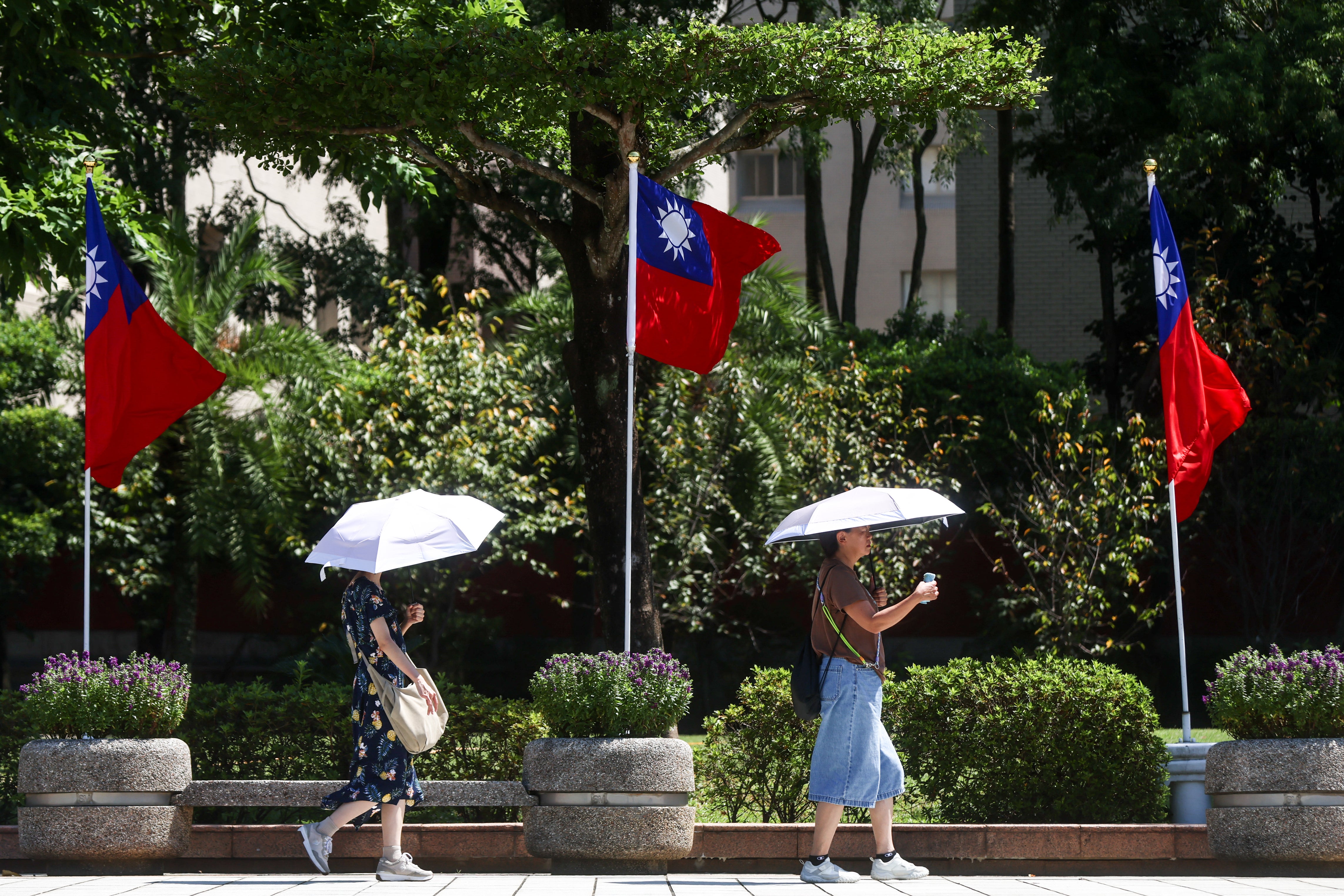 Visitors walk with umbrellas past Taiwanese national flags at the National Revolutionary Martyrs' Shrine in Taipei on September 23, 2026 (AFP/Getty)