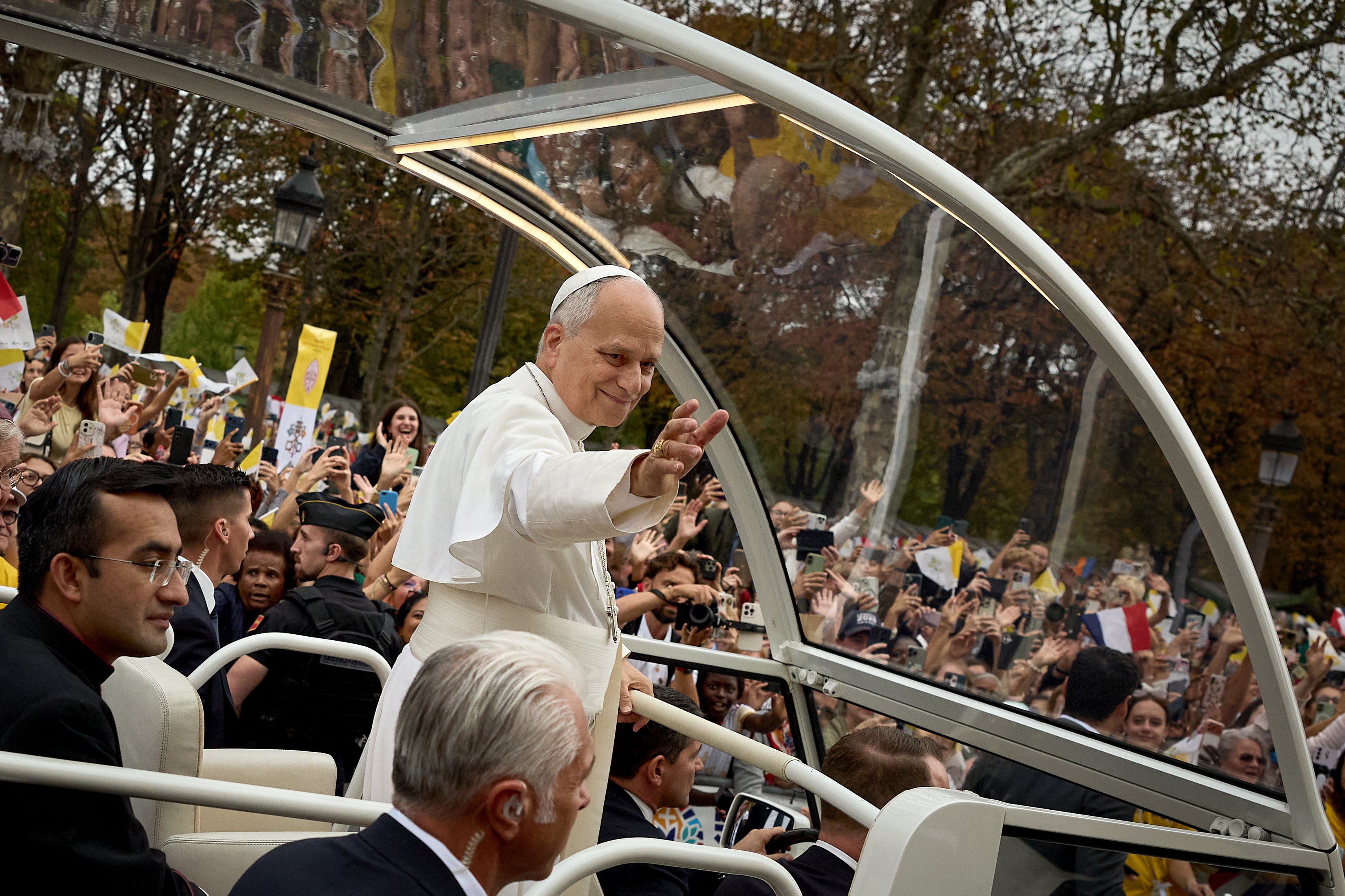Pope Leo XIV waves to the crowd from the popemobile as he rides down the Champs-Elysees Avenue