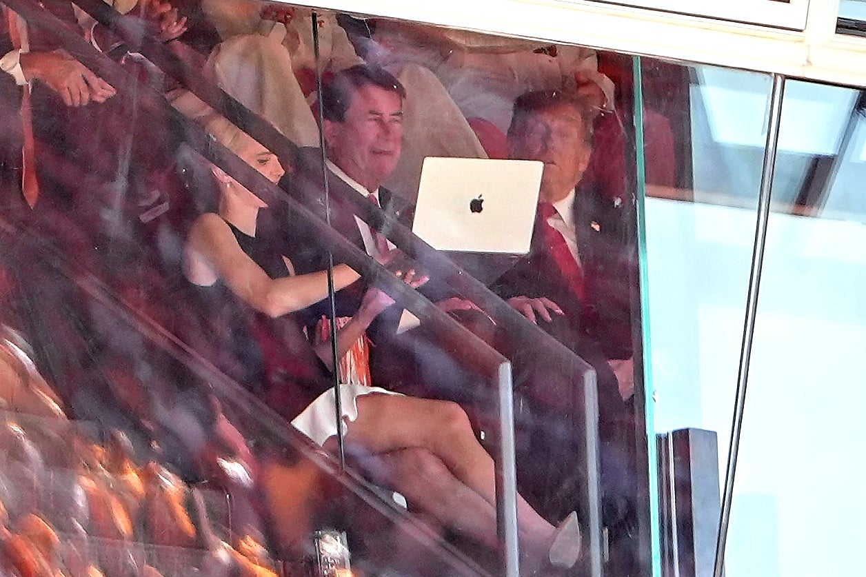 White House aide Natalie Harp, left, holds up a laptop for Trump, right, and Sen. Bill Hagerty, R-Tenn., center, during the game