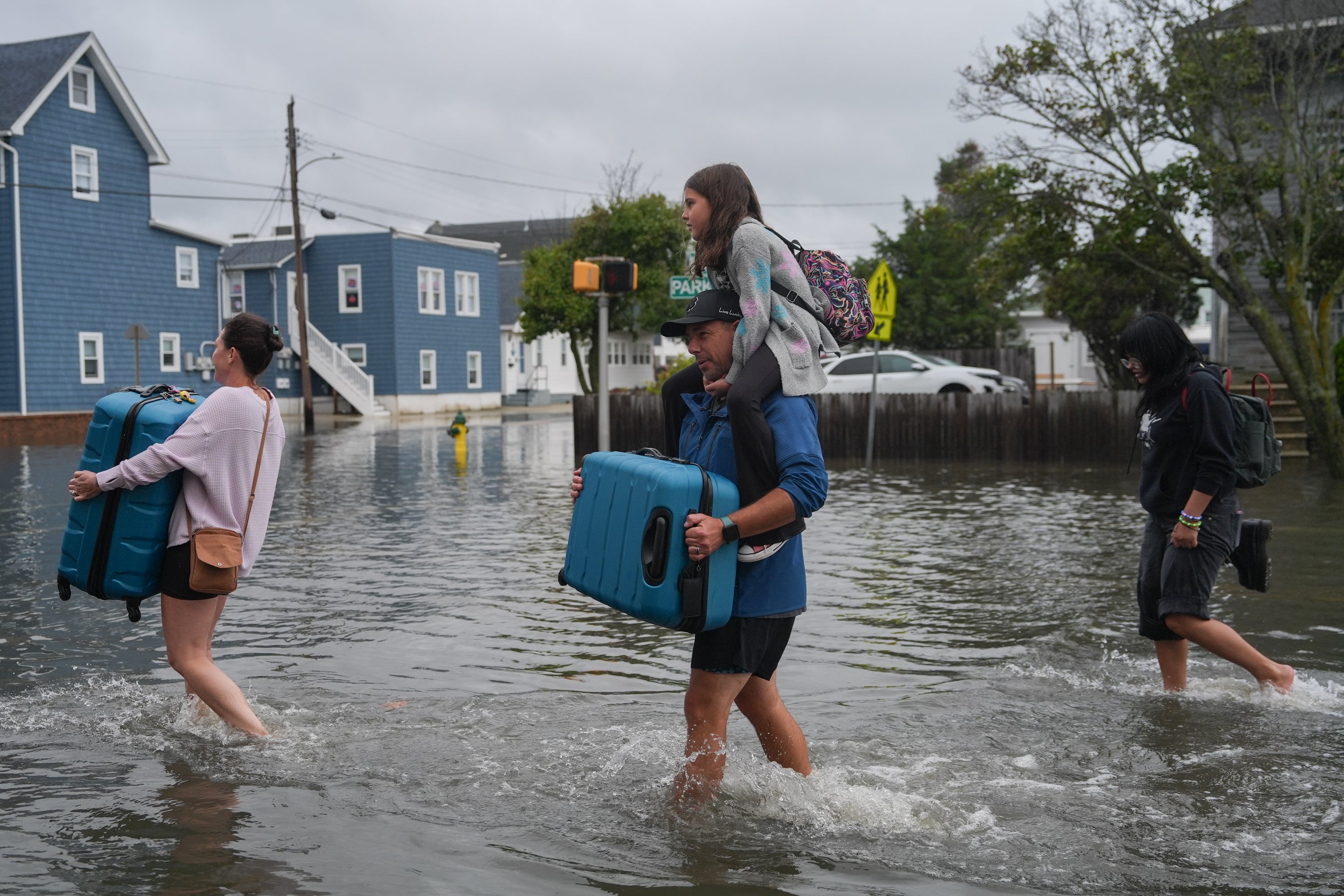 A family carries their belongings through the water of a flooded road during a nor'easter storm on September 26, 2026 in Point Pleasant, New Jersey