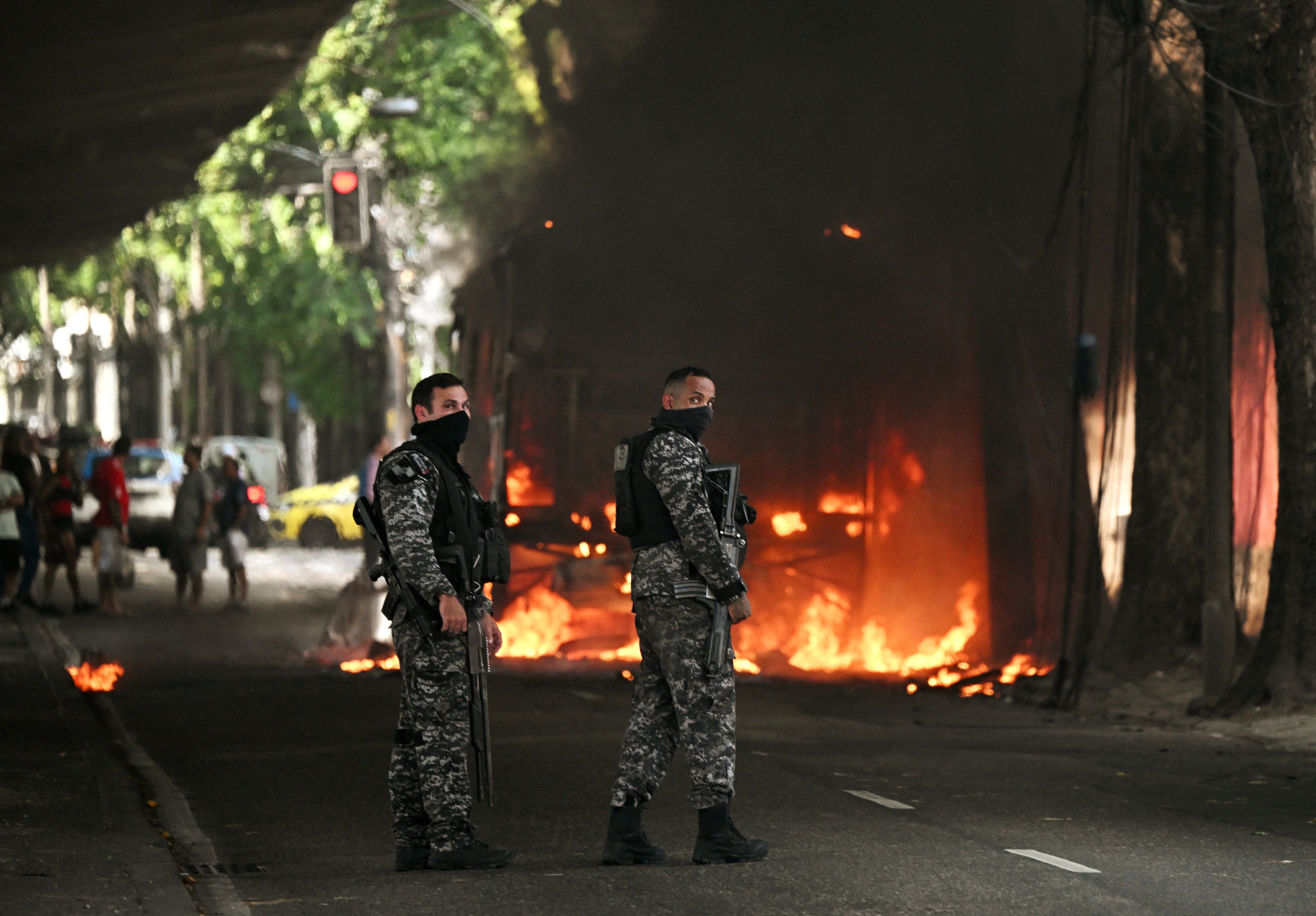 Police officers stand next to a bus set on fire by drug traffickers during a police operation in central Rio de Janeiro, Brazil, on March 18, 2026
