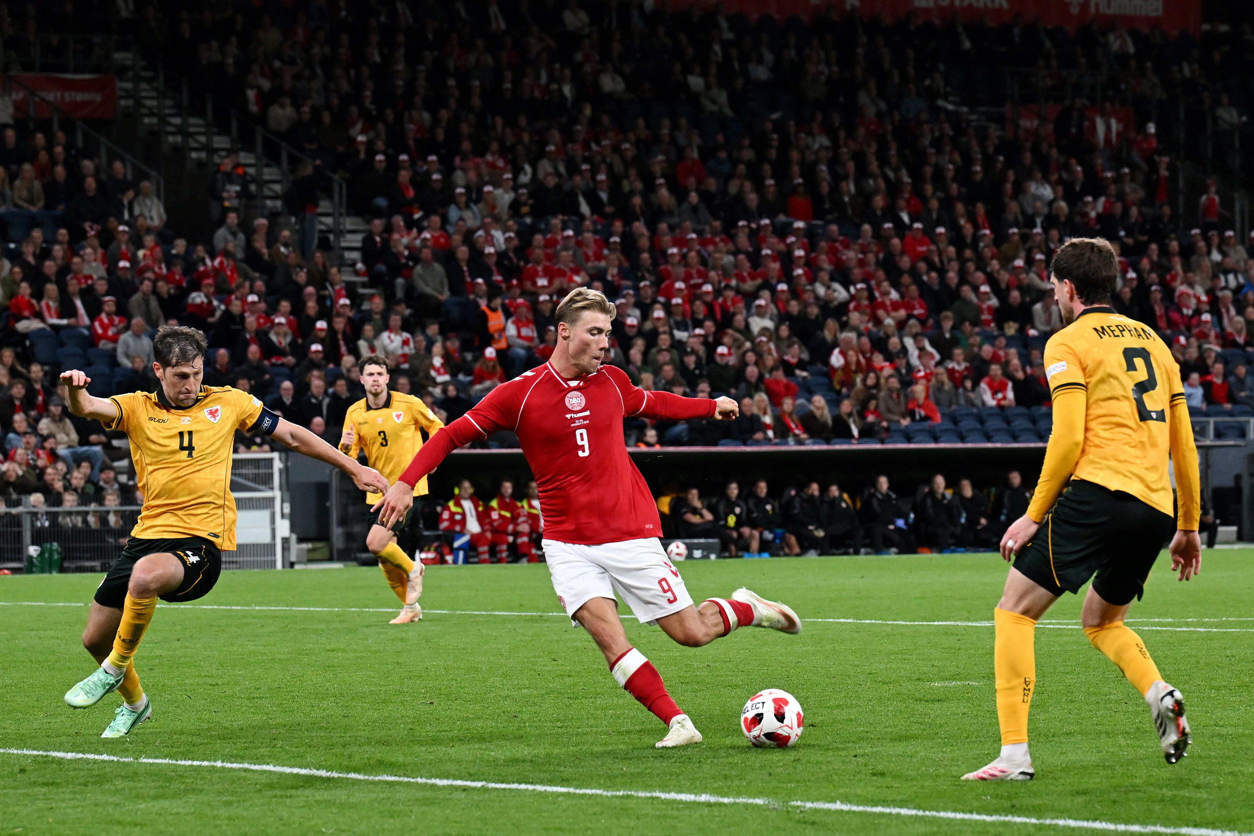 Rasmus Hojlund of Denmark shoots under pressure from Ben Davies of Wales