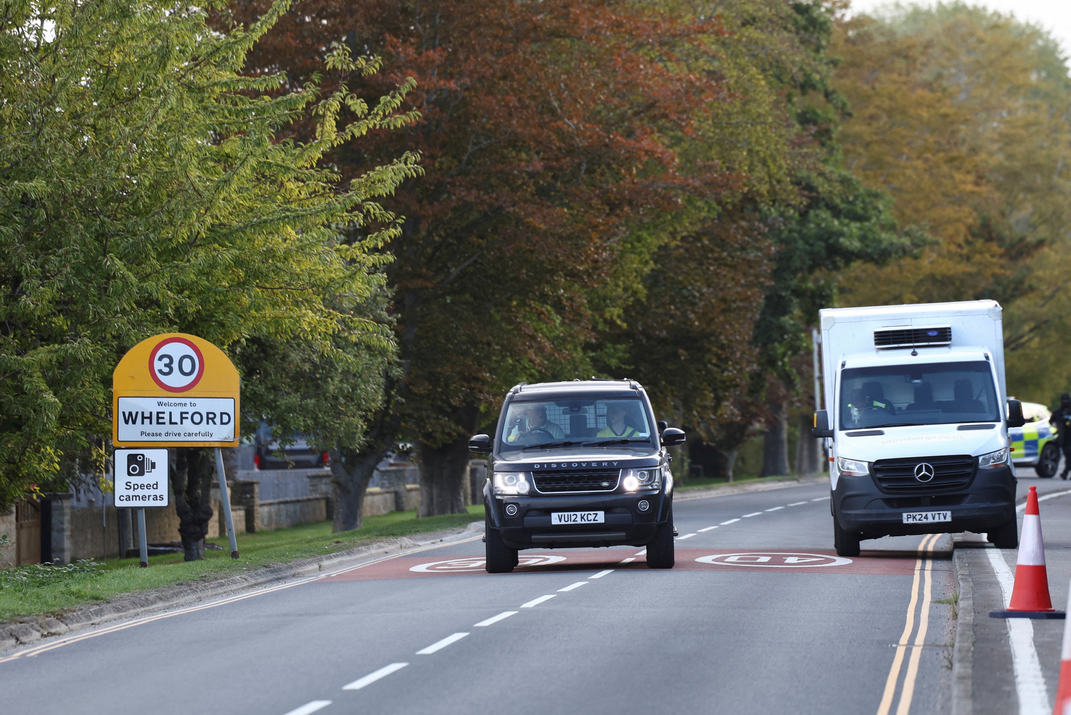 A vehicle drives past a Whelford sign as police block roads near the RAF Fairford