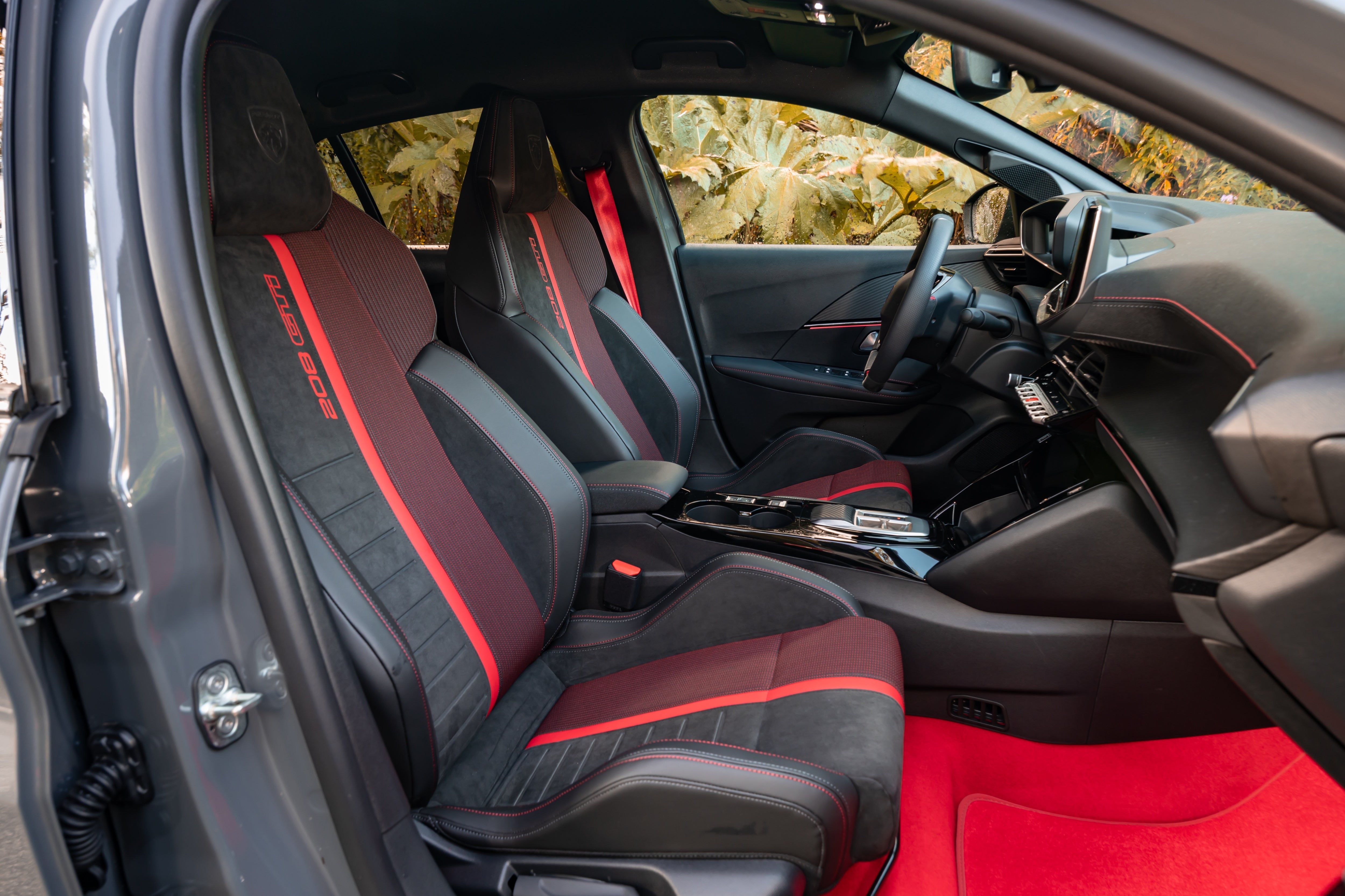 Red seatbelts, red carpets, red mats and red stripes around the cabin. There's a definite theme inside the Peugeot E-208 GTI (Peugeot)