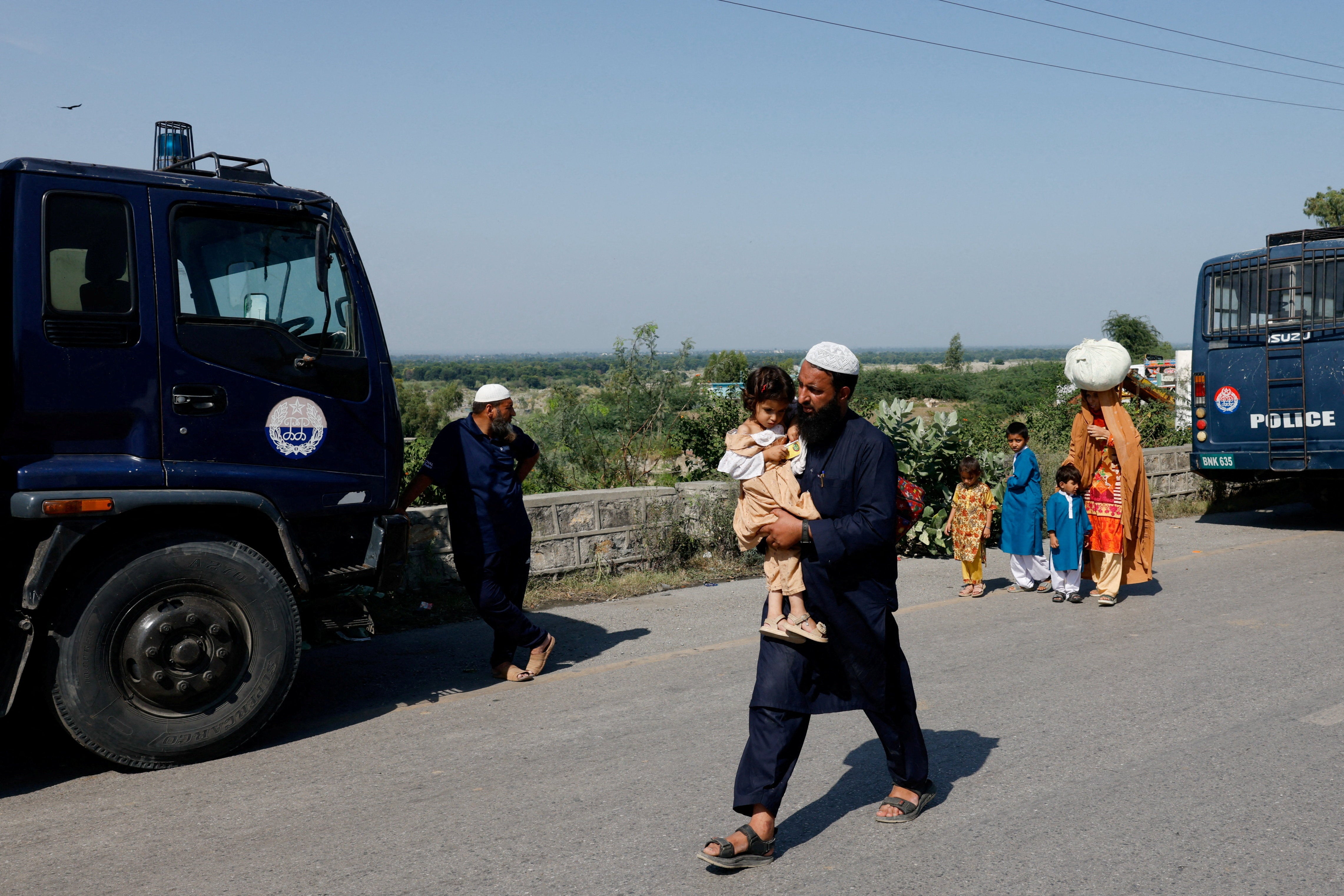 A family walks as police closed the Grand Trunk Road ahead of a planned march by Imran Khan's party from Peshawar to Islamabad on 25 September 2026 (Reuters)