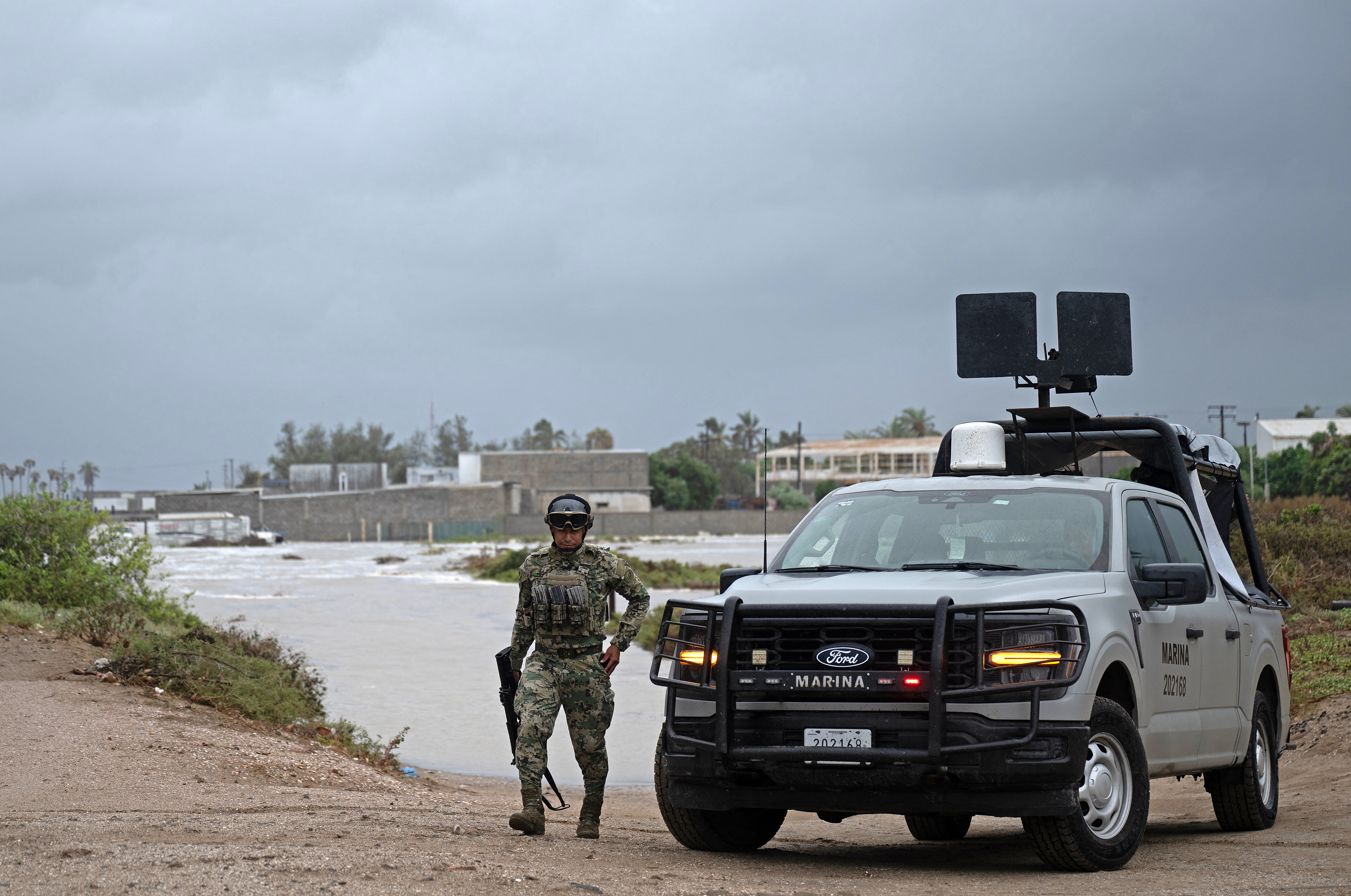 A member of Mexico's Navy walks away from a levy which broke due to a surge in water levels in Puerto San Carlos, Baja California Sur