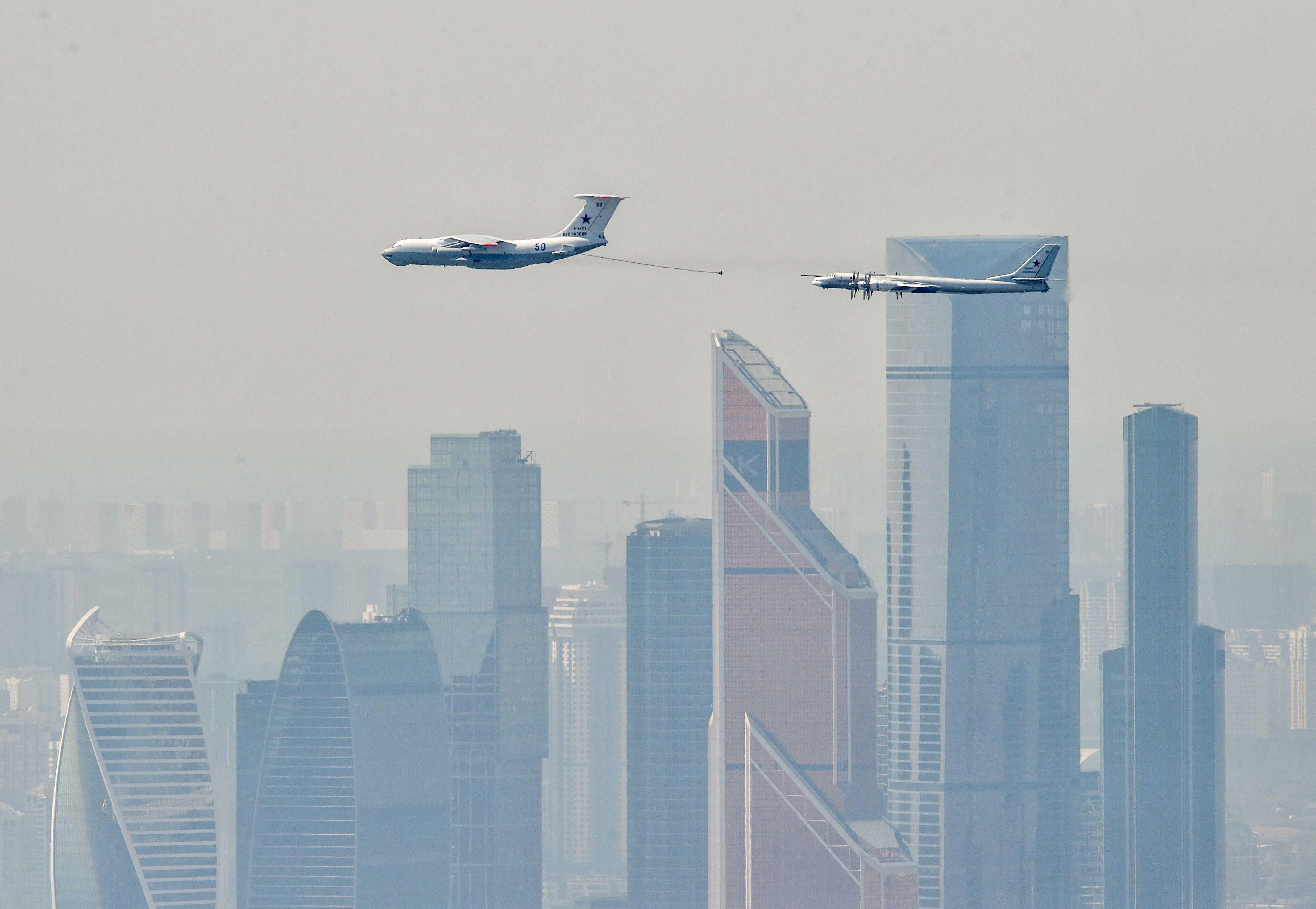 A Russian IL-78 tanker (right) approaches to refill a TU-95MS bomber flying over skyscrapers of the Moscow International Business Centre (Moskva City) on May 7, 2019