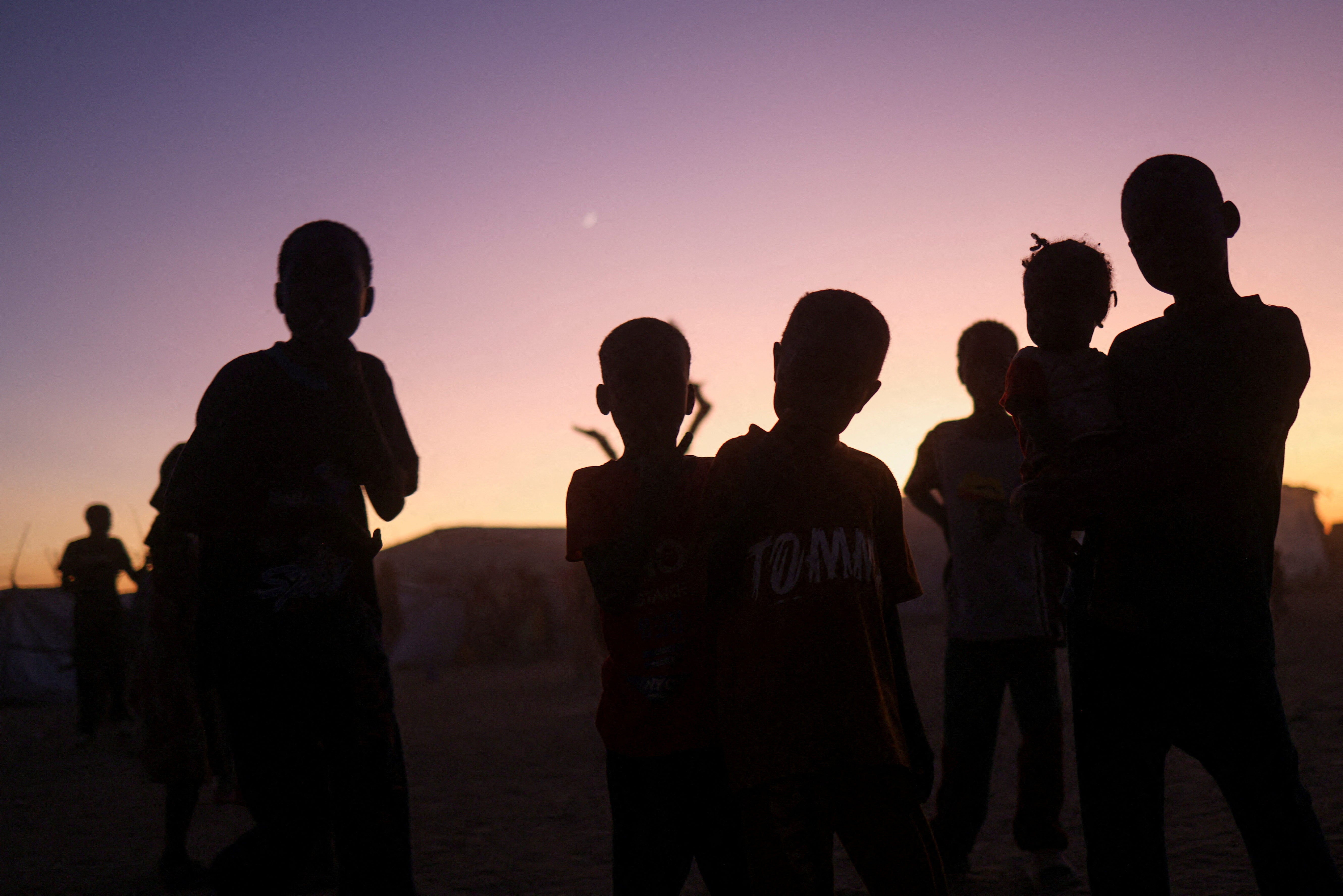 Sudanese refugee children stand at sunset in the Tine transit camp