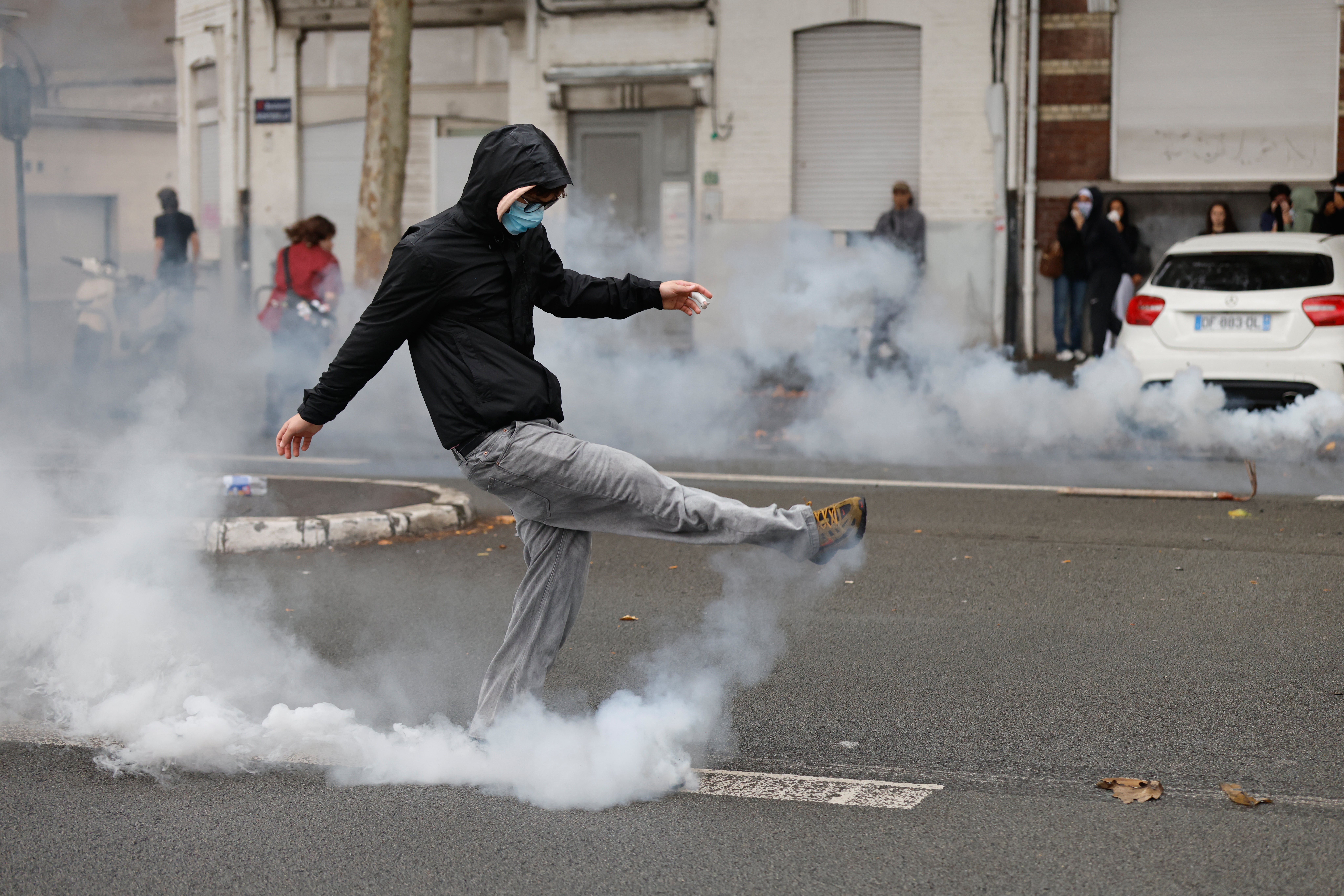 A student kicks a tear gas canister in protests in Lille, demanding more resources for schools