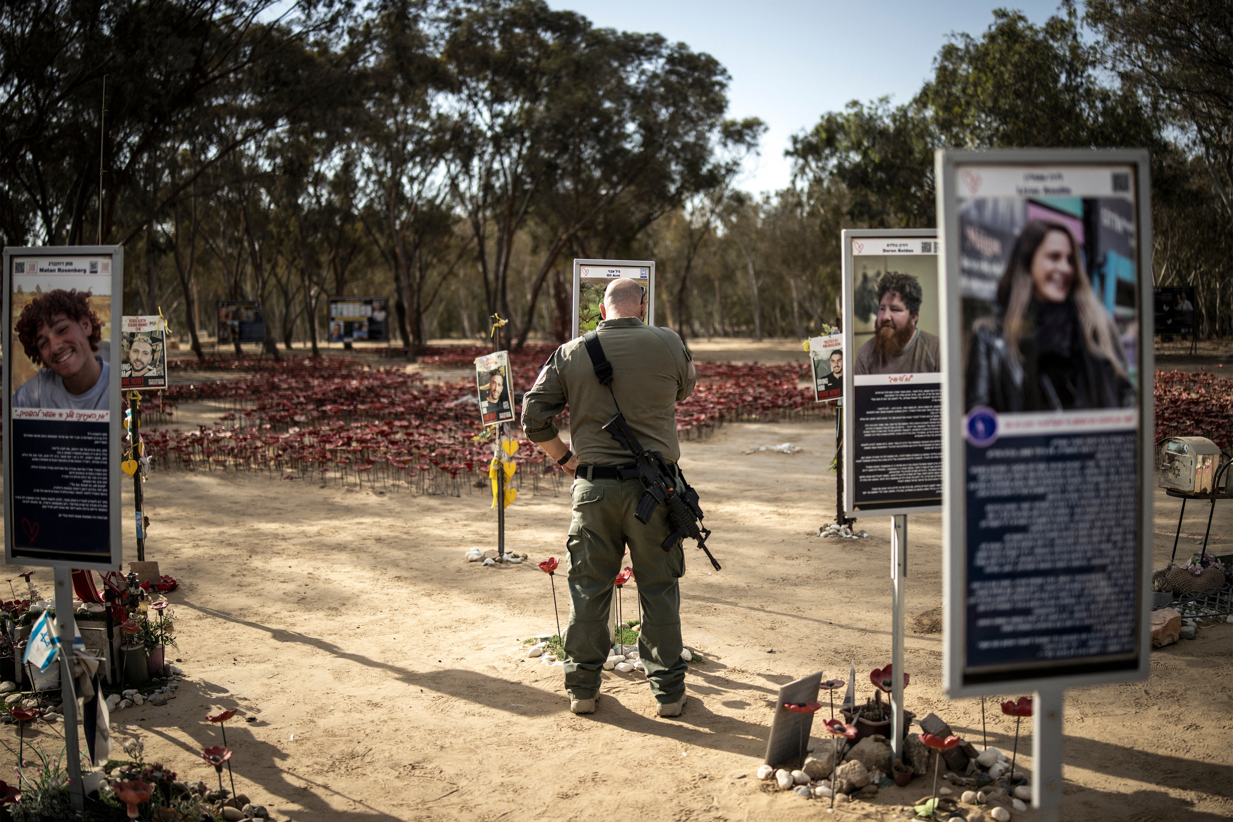 An Israeli army soldier pays his respects to the memorial of a victim of the October 7 attacks in Reim
