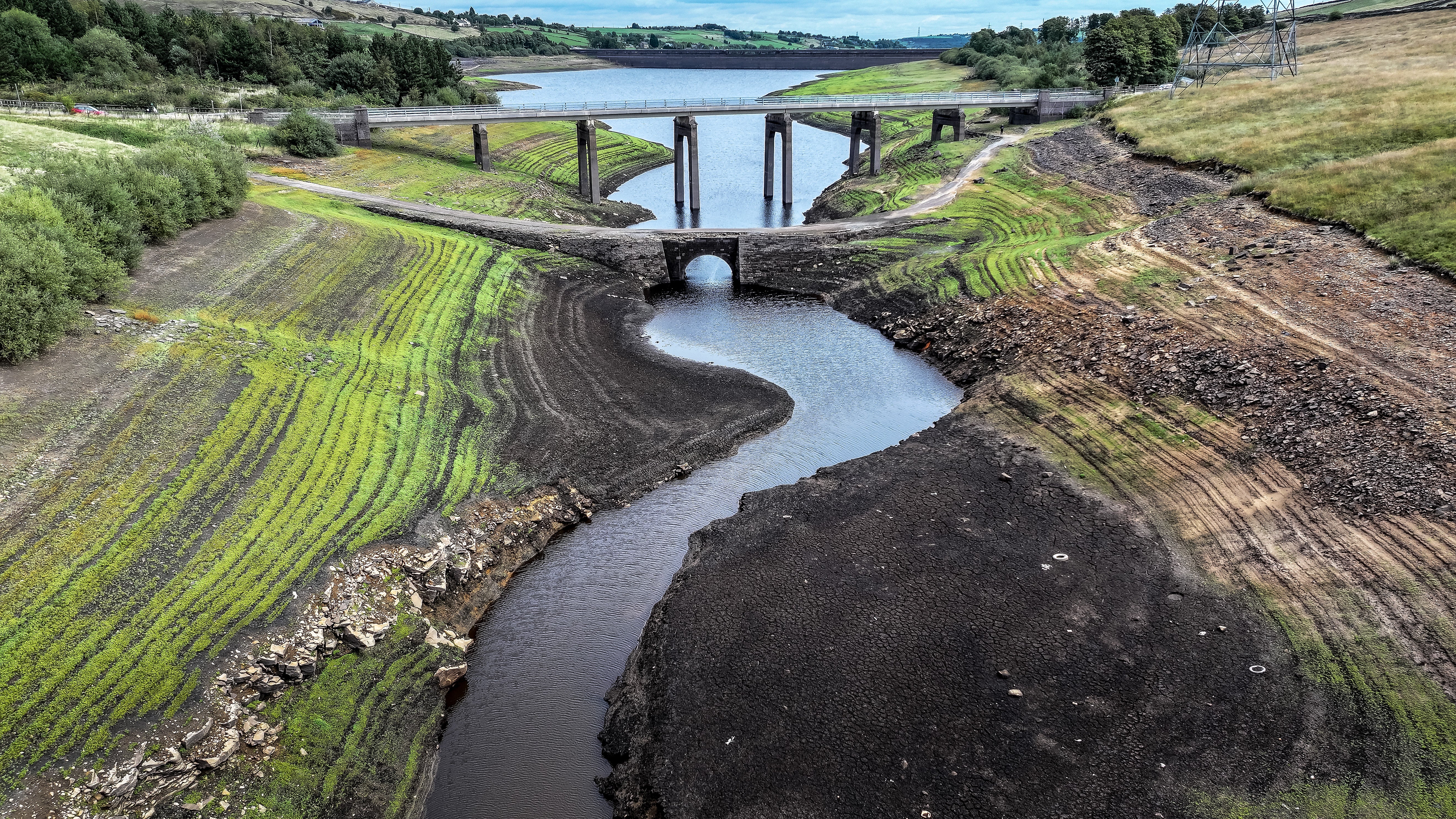 An ancient packhorse bridge is revealed by low water levels and allows vegetation to grow on the bed of Baitings Reservoir on September 14, 2026 near Ripponden, England (Getty)