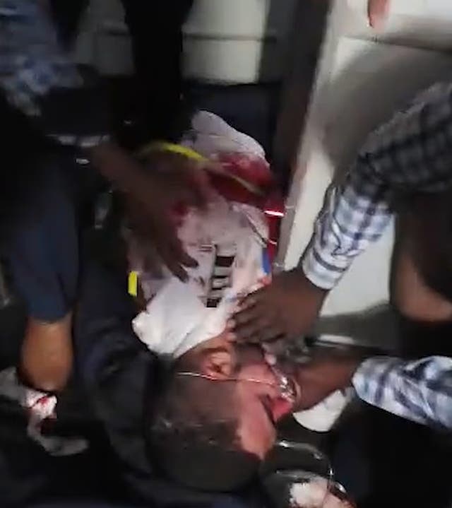 Passengers gather round an injured man, who appears to be one of the pilots