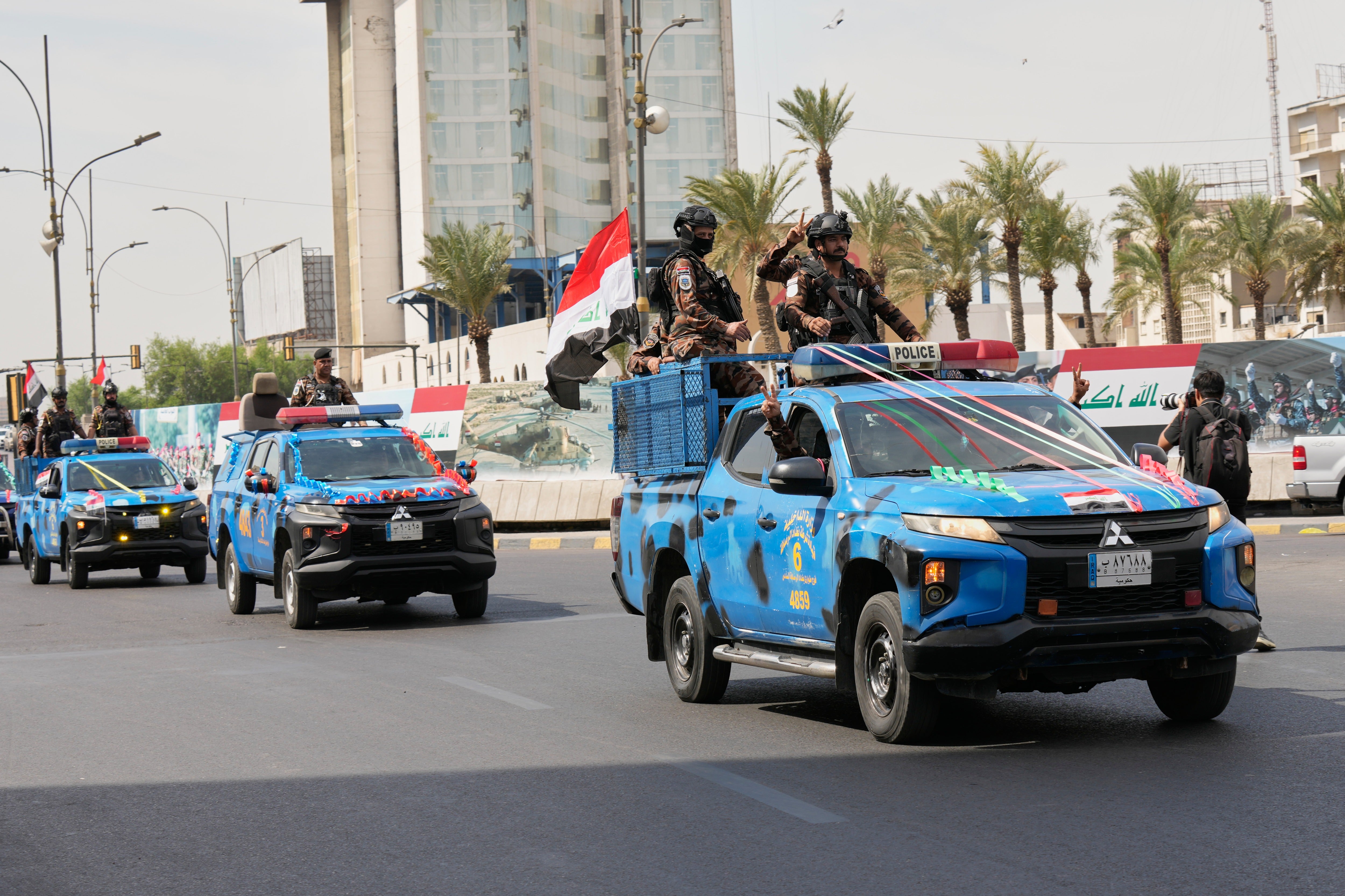Iraqi police vehicles decorated with national flags and ribbons drive in a convoy as officers flash victory signs while celebrating the complete withdrawal of U.S. troops from Iraq