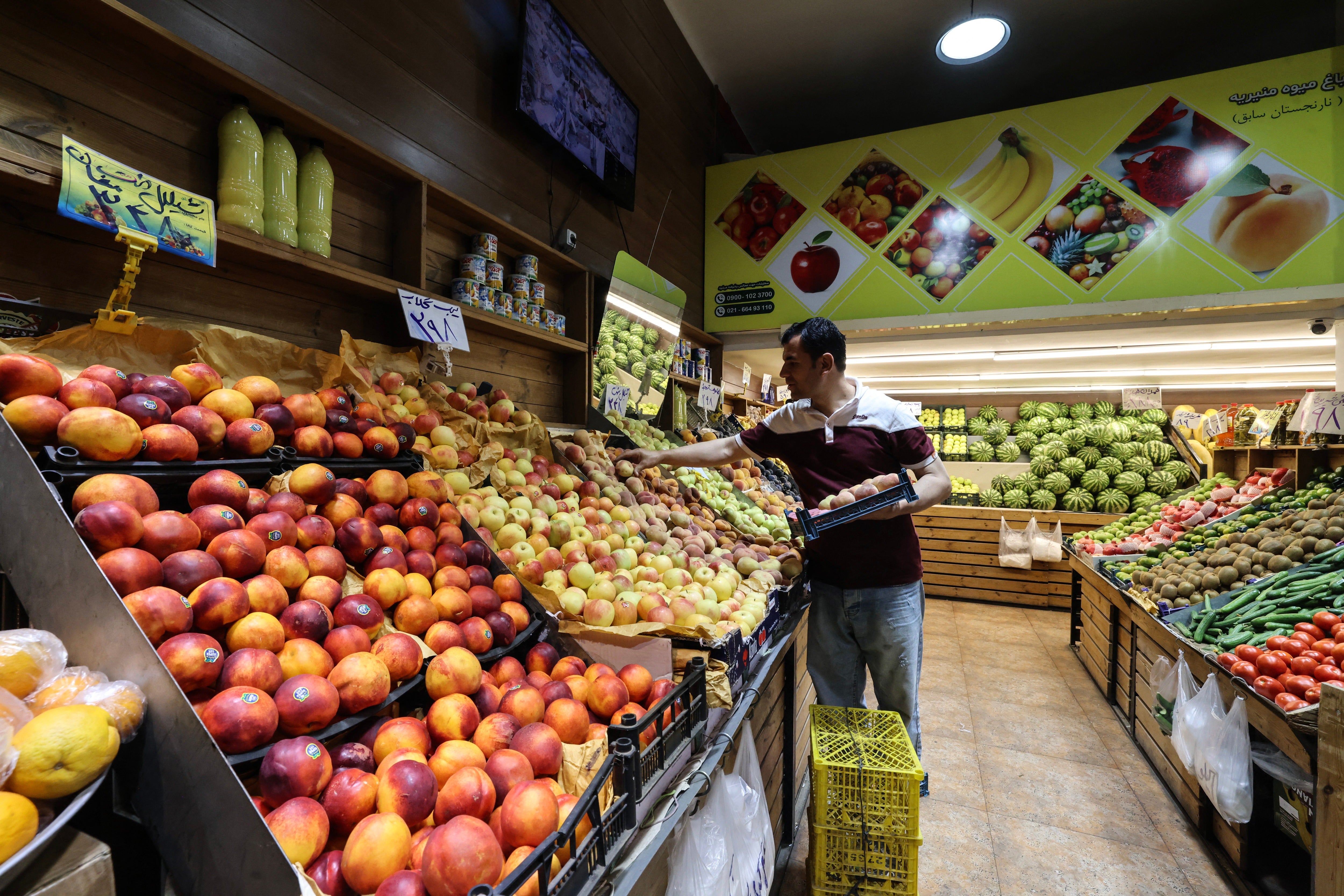 A man arranges fruit at a grocery store in southern Tehran