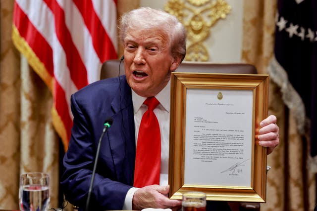 President Donald Trump holds a framed letter from Argentina’s President Javier Milei stating that Milei nominates Trump for the Nobel Peace Prize