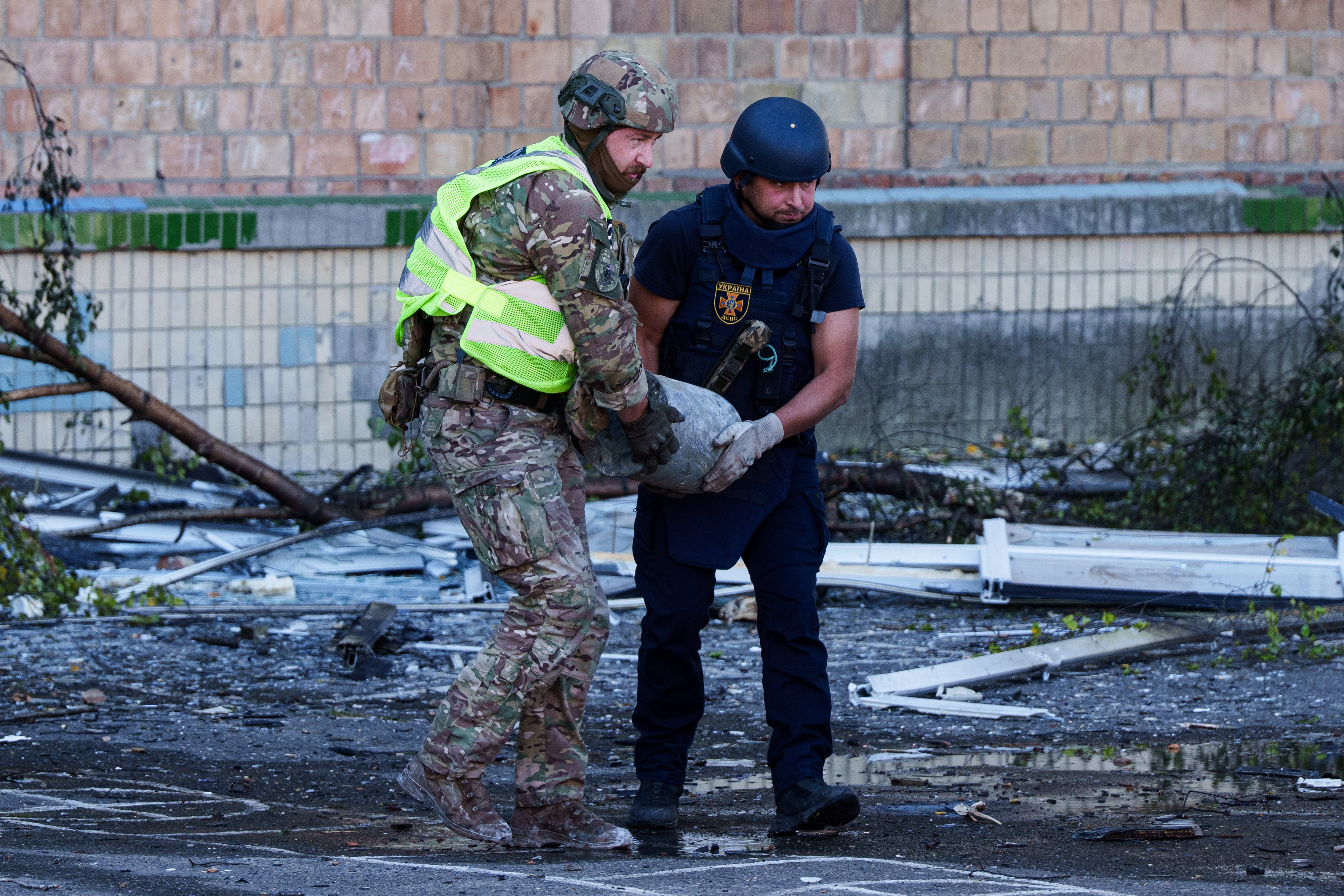 A police officer and a rescue worker carry an unexploded warhead from a Shahed drone out of a school damaged by a Russian strike on Kyiv, Ukraine, 1 Oct 2026