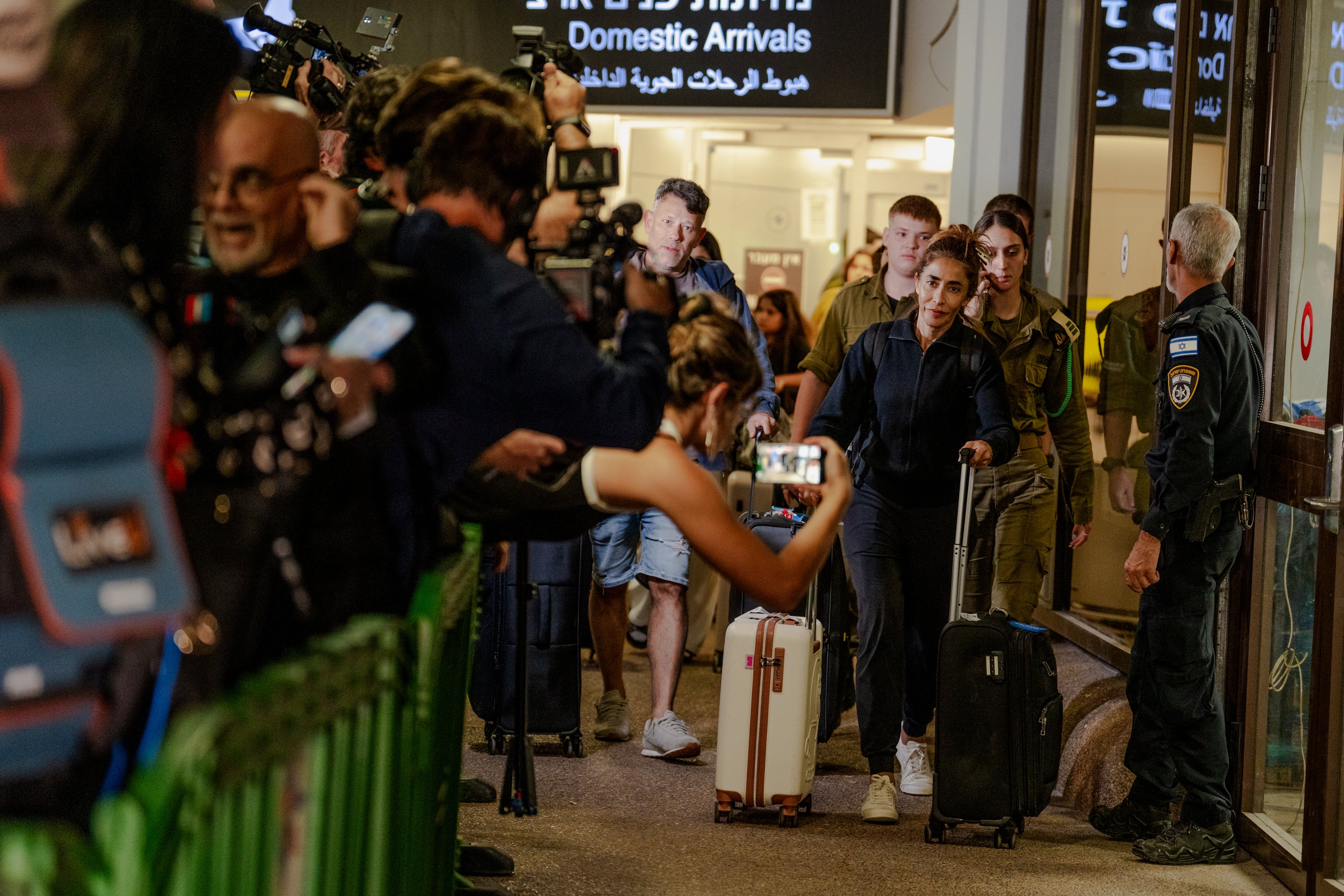 Passengers pull suitcases through a media scrum outside the terminal after arriving on a Flydubai retrieval flight at Ben Gurion Airport (Getty)