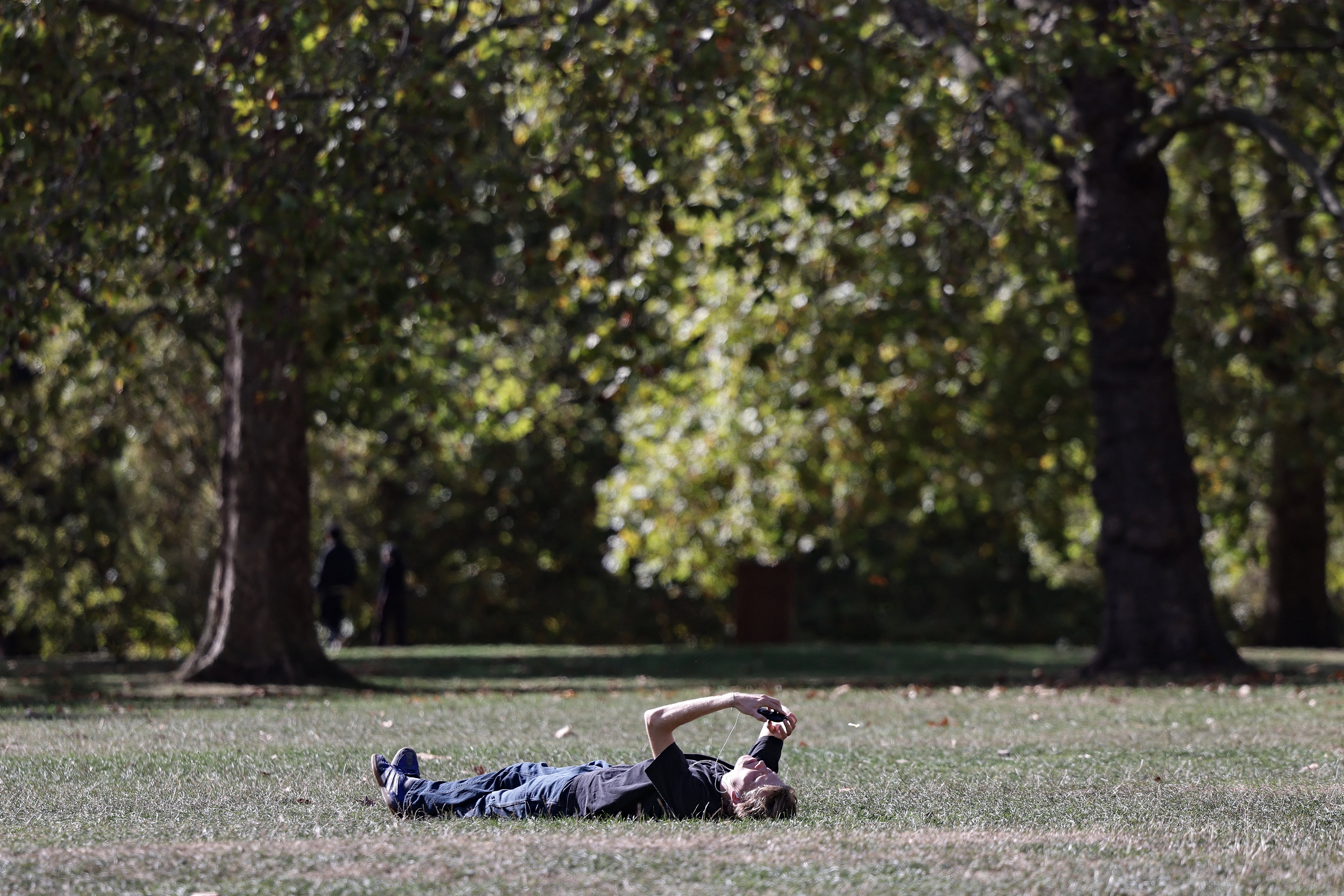 A man rests in a park in central London on October 1, 2026, as temperatures reached 20C following a record warm summer