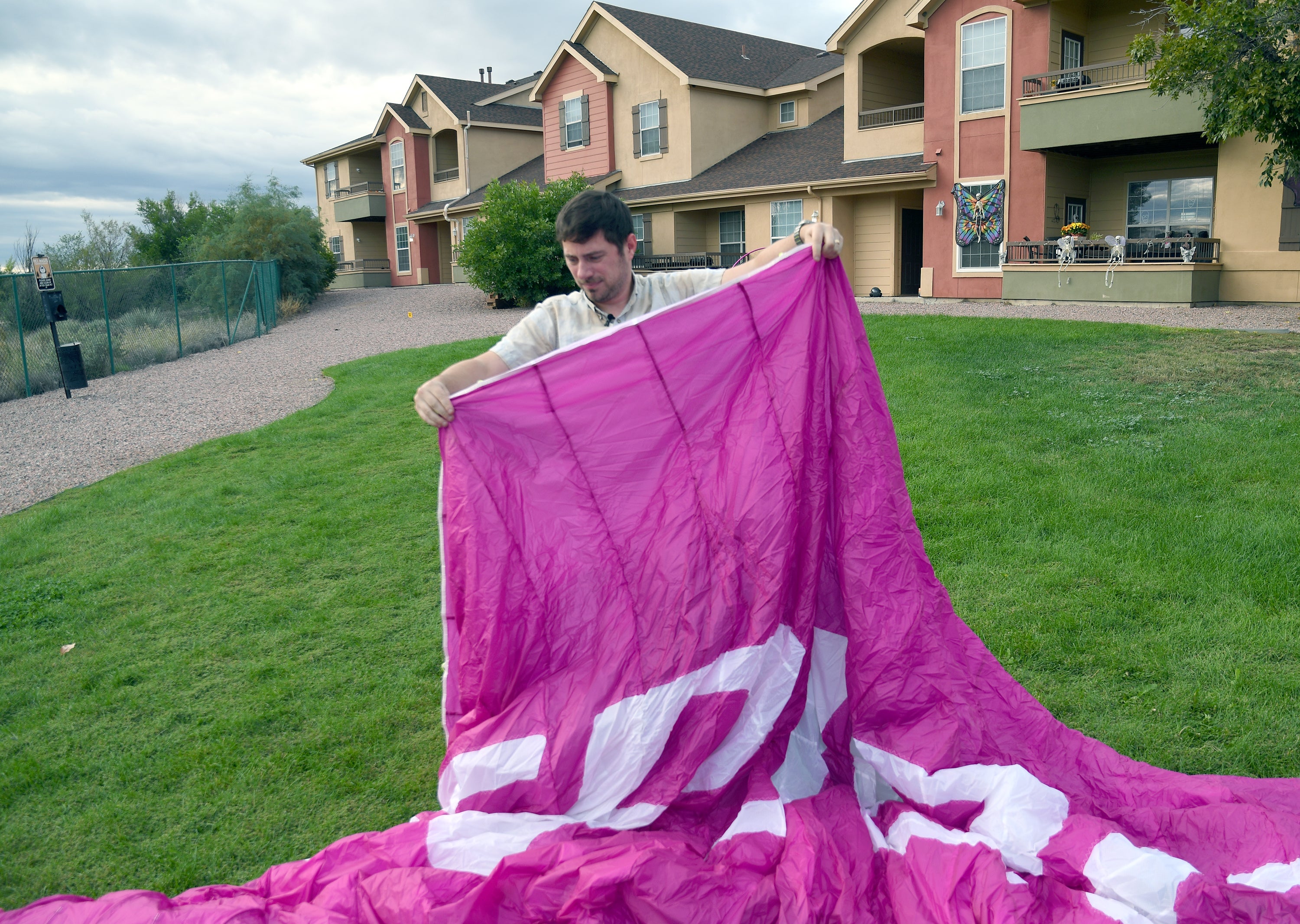 Jake Hutzler, who often flies to his air traffic controller job, shakes sand from his paramotor wing outside his home in Pueblo, Colo., on Thursday, Oct. 1, 2026. (AP Photo/Thomas Peipert)