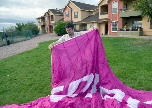 Jake Hutzler, who often flies to his air traffic controller job, shakes sand from his paramotor wing outside his home in Pueblo, Colo., on Thursday, Oct. 1, 2026. (AP Photo/Thomas Peipert)