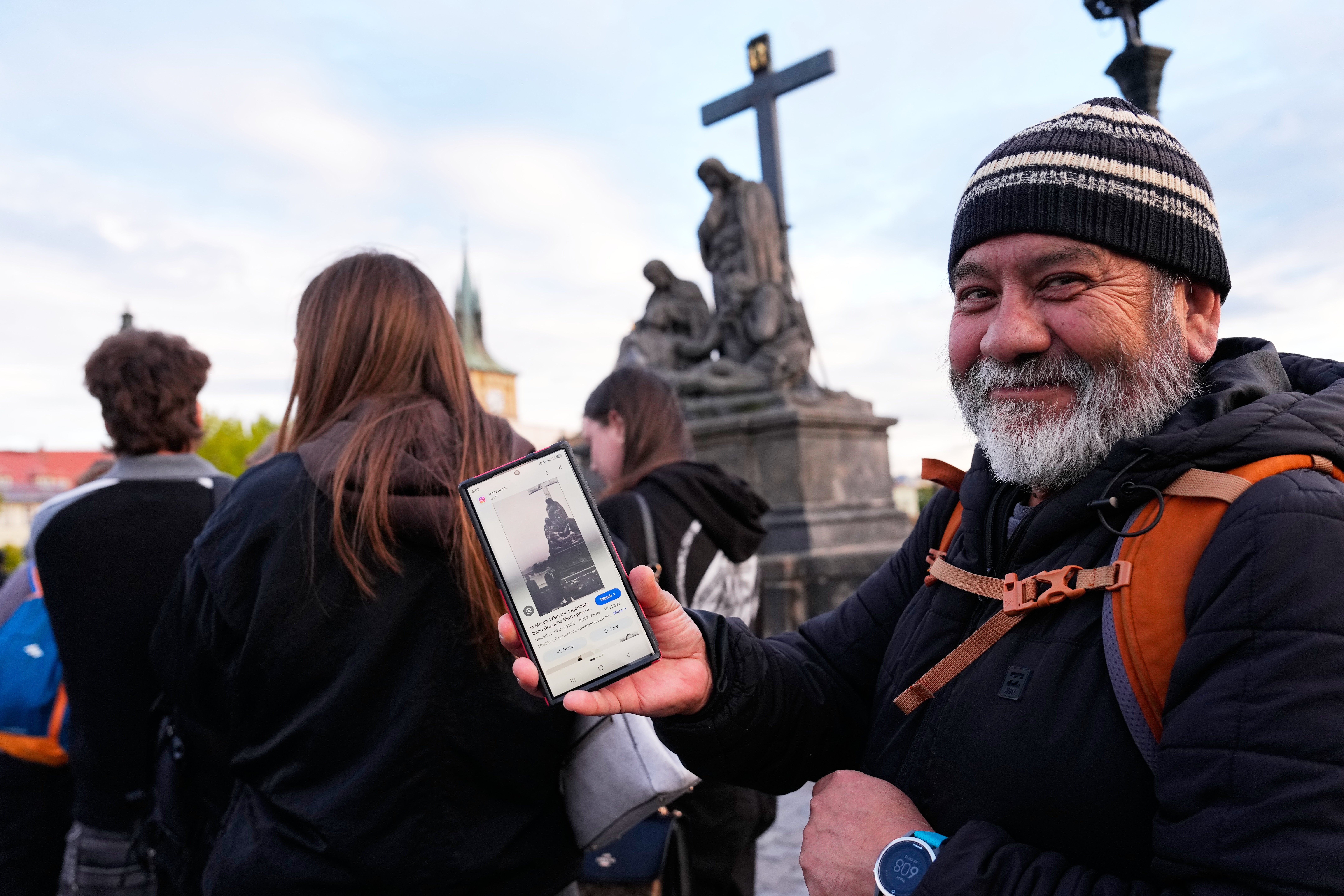 Jorge Sanchez from Los Angeles displays a famous photo of two members of Depeche Mode, taken by Dutch photographer Anton Corbijn in 1988, as he waits in line to recreate this image by the Pieta statue at the Charles Bridge in Prague, Czech Republic
