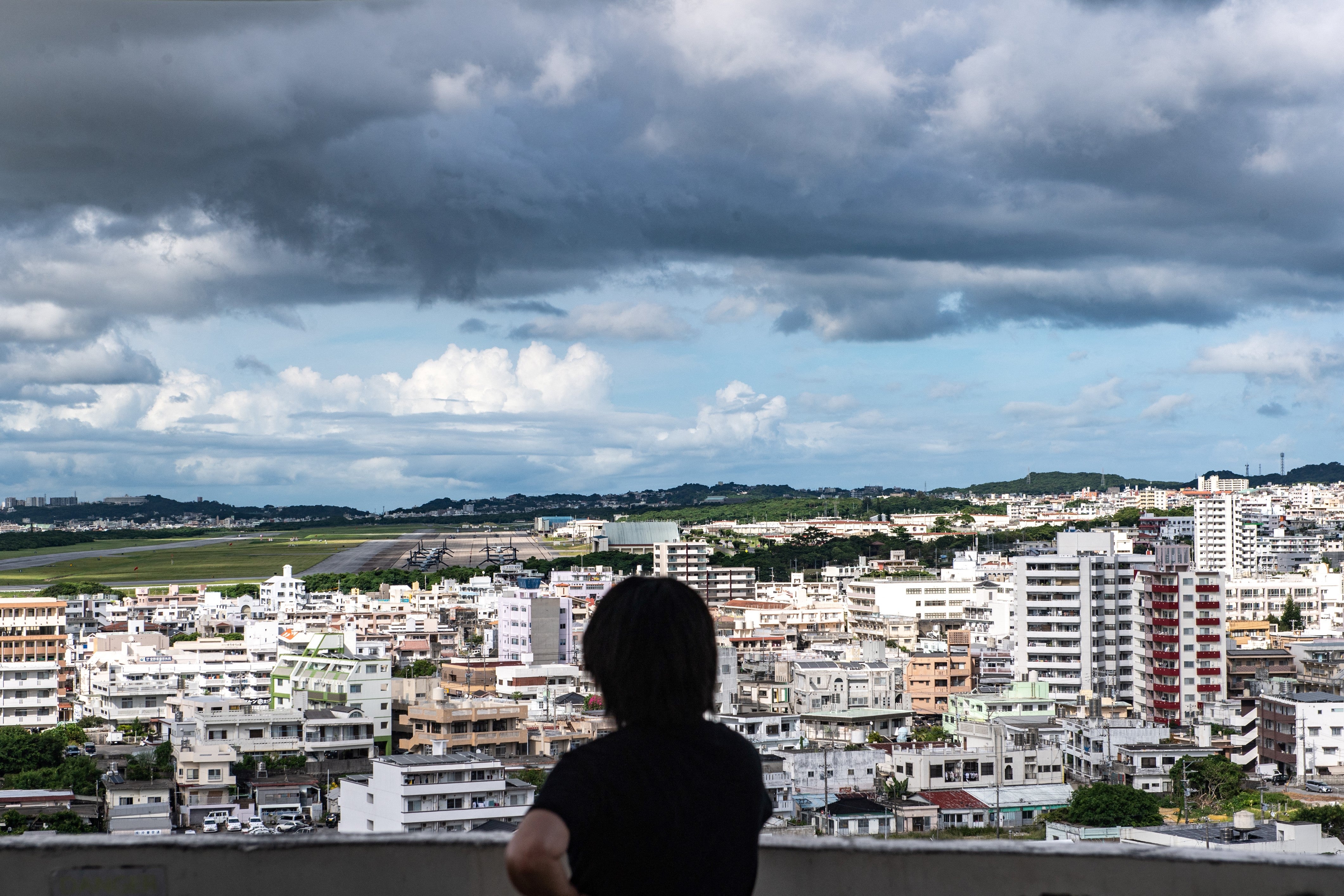 Person looking out at the US Marine Corps Air Station Futenma from Kakazutakadai Park in Ginowan