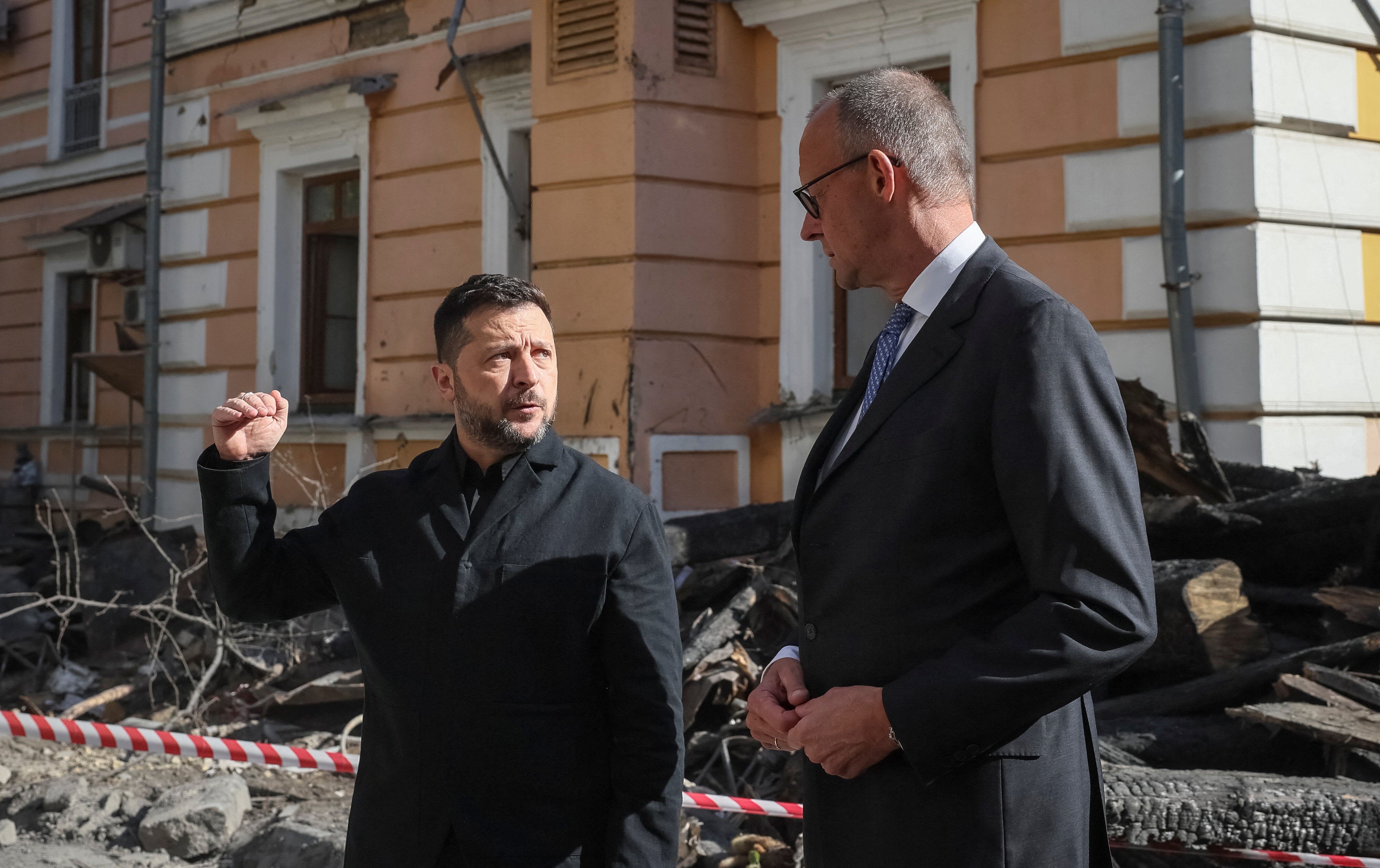 Ukraine's President Volodymyr Zelenskiy and German Chancellor Friedrich Merz visit the site of an administrative building of Ukraine's National Academy of Sciences hit during recent Russian drone strikes