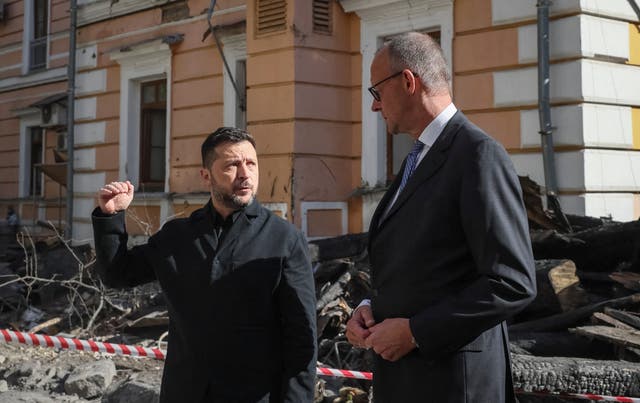 Ukraine's President Volodymyr Zelenskiy and German Chancellor Friedrich Merz visit the site of an administrative building of Ukraine's National Academy of Sciences hit during recent Russian drone strikes