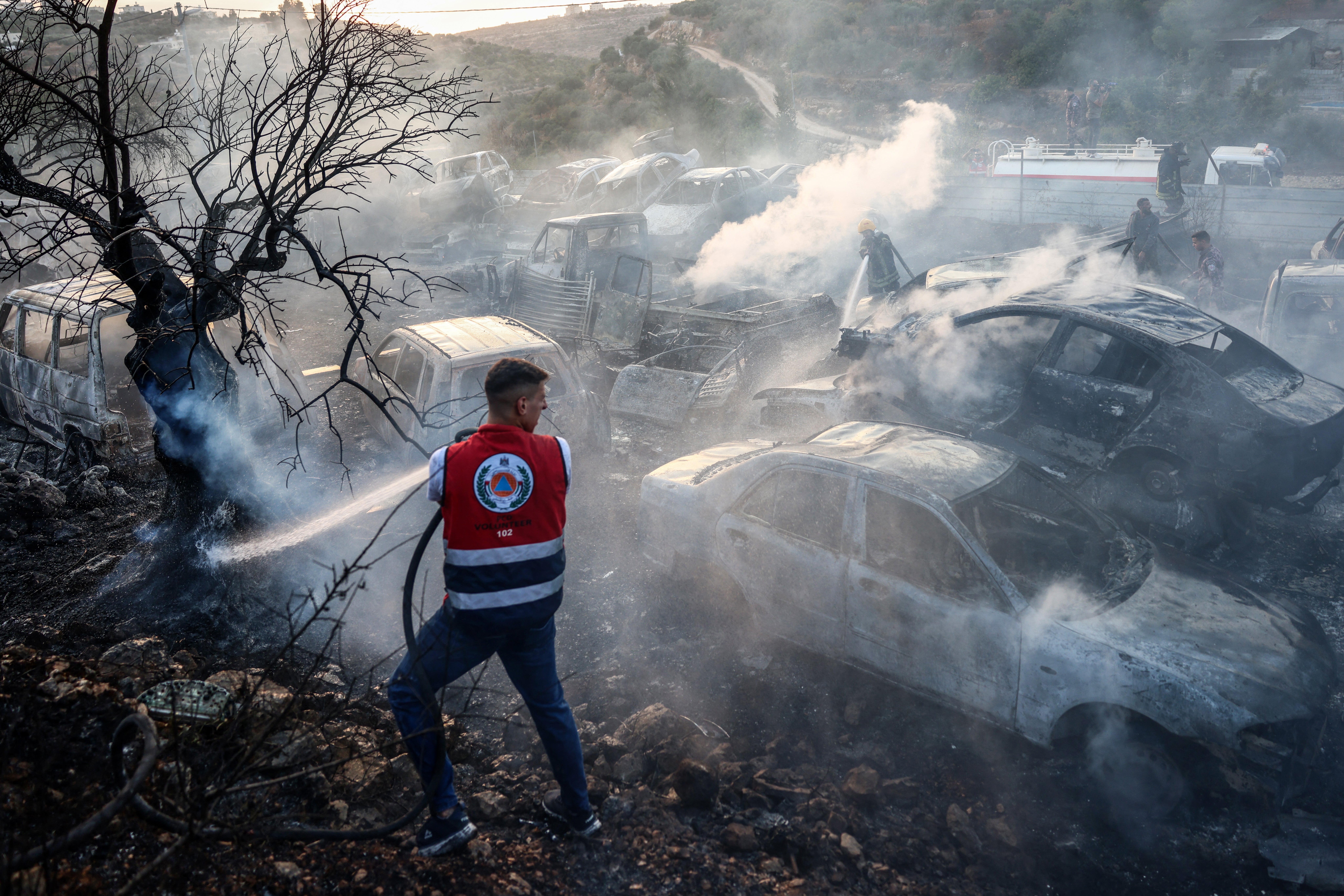 A Palestinian man helps put out a fire that burnt through cars and olive trees at a scrapyard following an attack allegedly carried out by Israeli settlers in the village of Ayn Yabrud, northeast of Ramallah, in the Israeli-occupied West Bank, on October 4, 2026 (AFP/Getty)