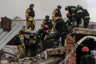 Rescuers carry the body of a killed person found under debris of a sewing factory which was hit by a Russian airstrike