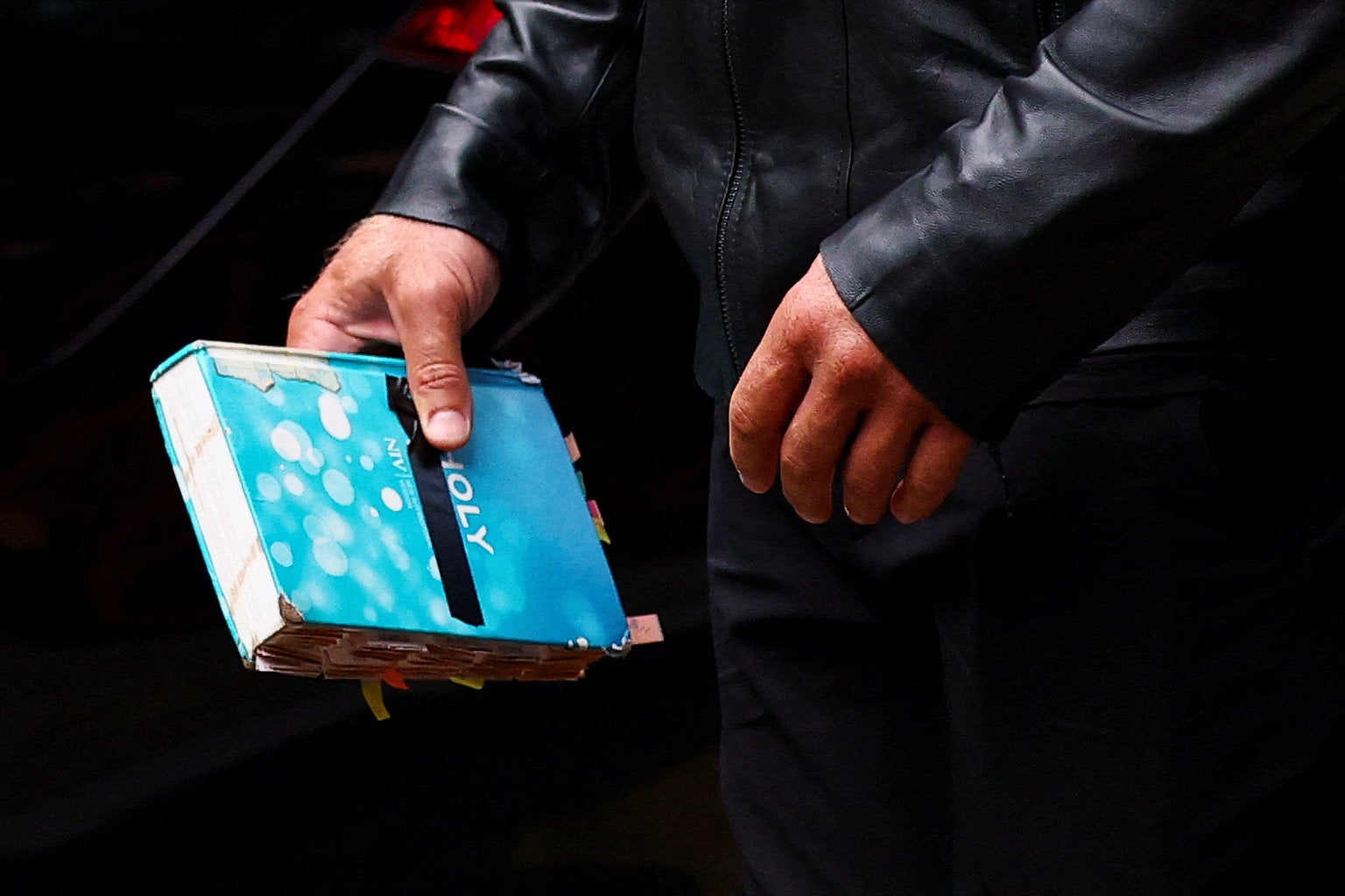 Russell Brand’s bodyguard holds a Bible as they make their way into court