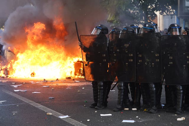 Riot police stand in formation as fires burn in the streets of Paris