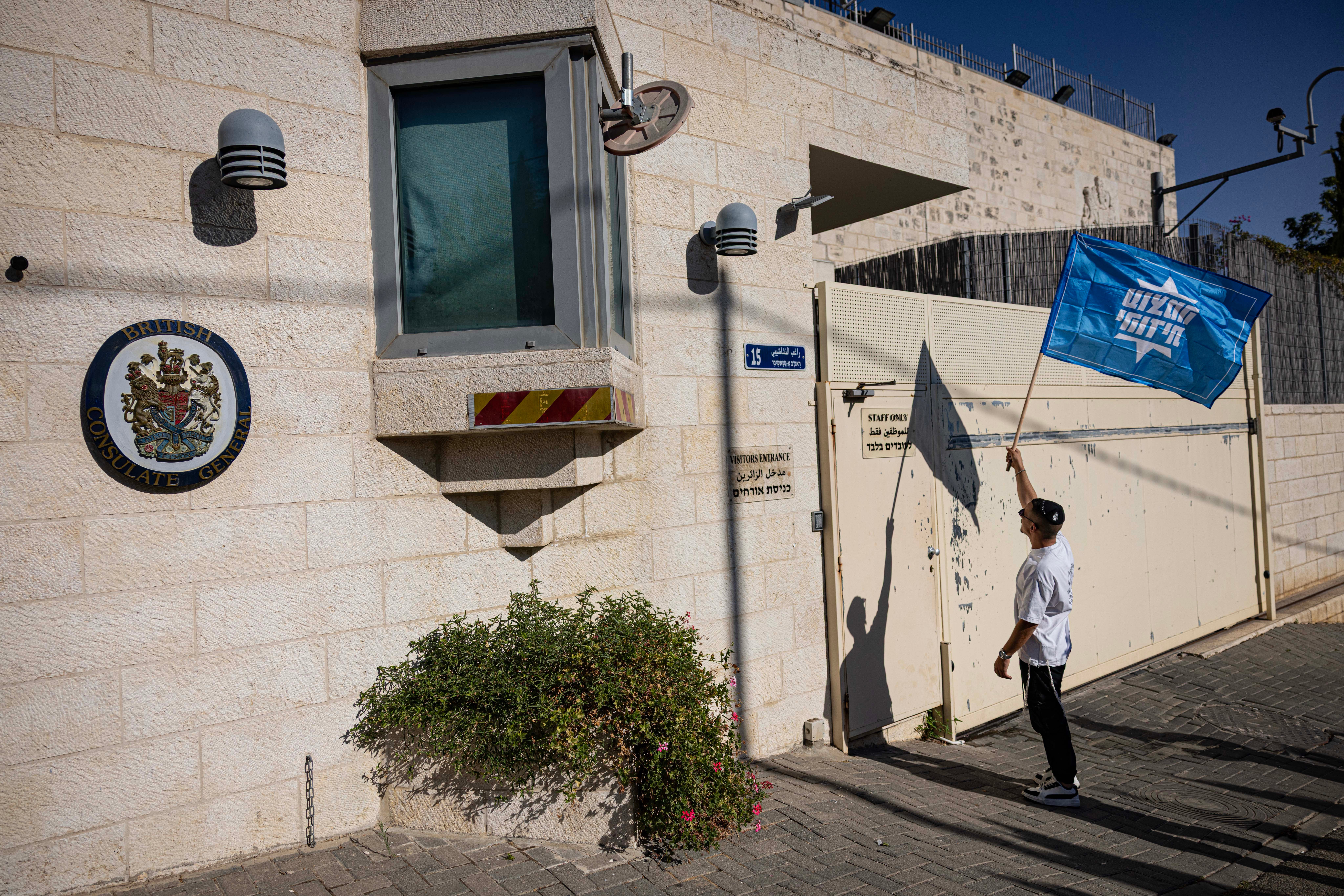 An Israeli far-right activist holds an Otzma Yehudit flag outside the British Consulate during a protest against the recently announced British sanctions.