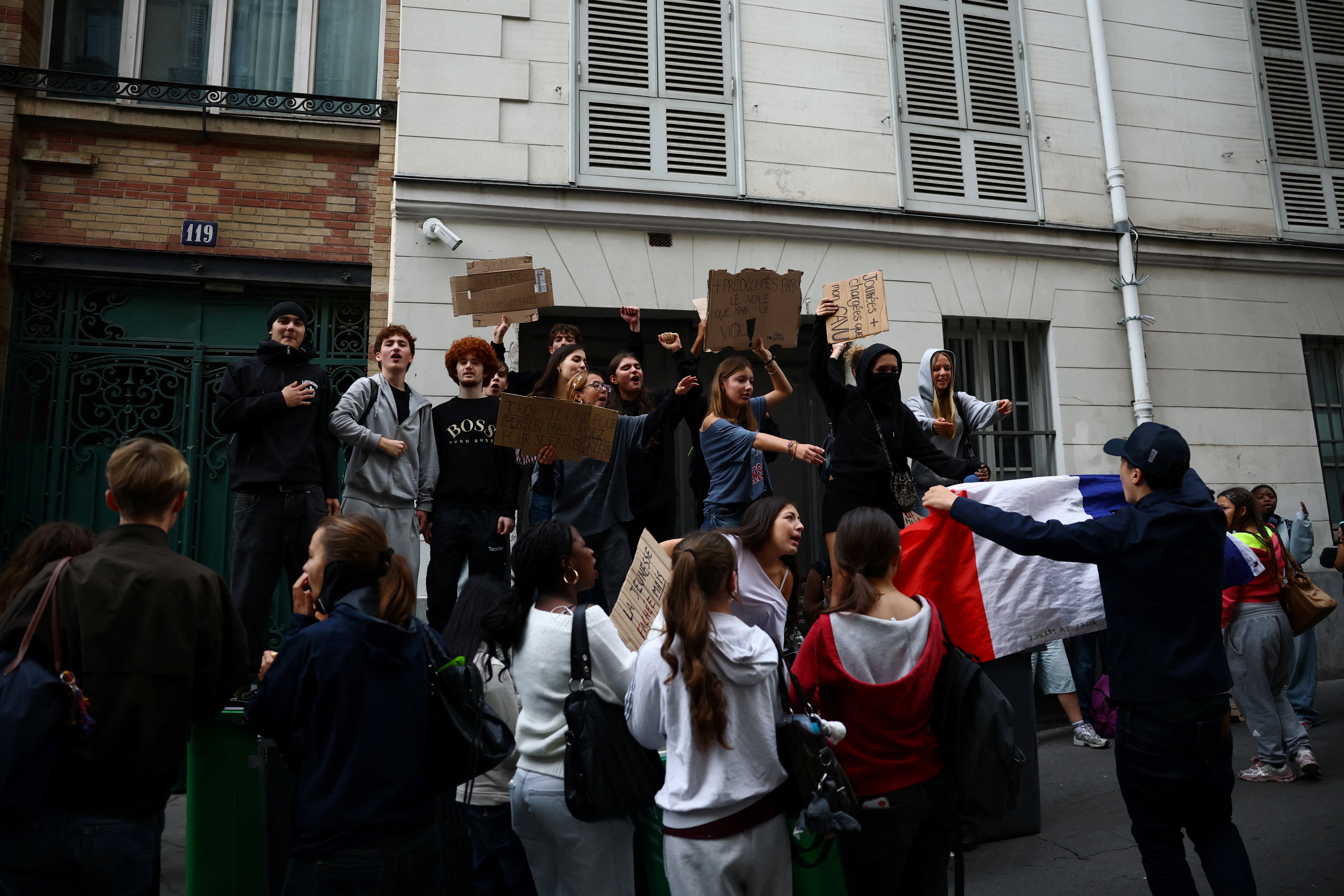French high school students hold a French flag and placards as they gather outside the Lycée Lamartine high school in Paris as part of nationwide protests to demand better school conditions in France, 7 October 2026