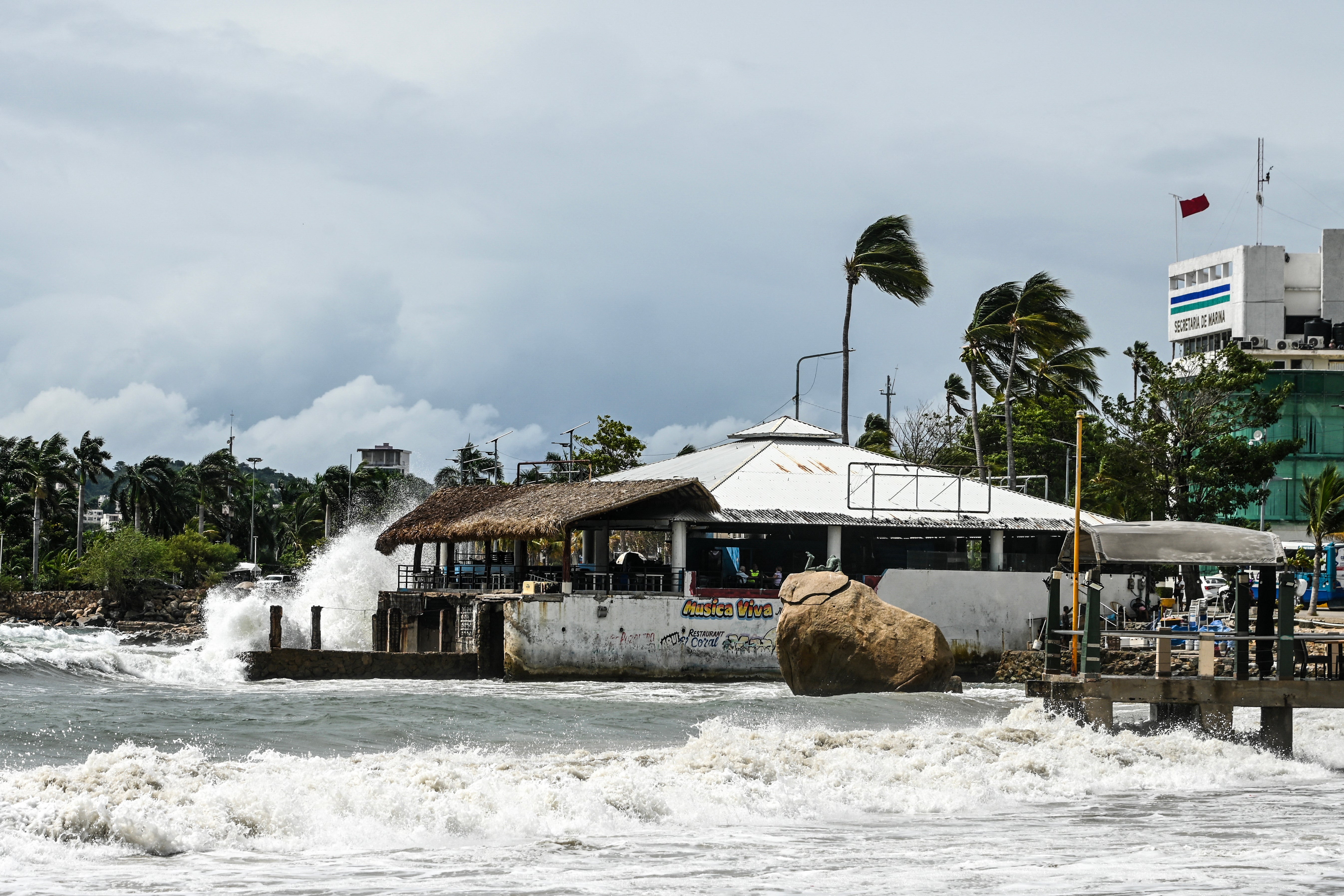 High waves crash against the waterfront as a red warning flag (R) flies outside the port captain's office in the tourist port of Acapulco, Guerrero state, Mexico