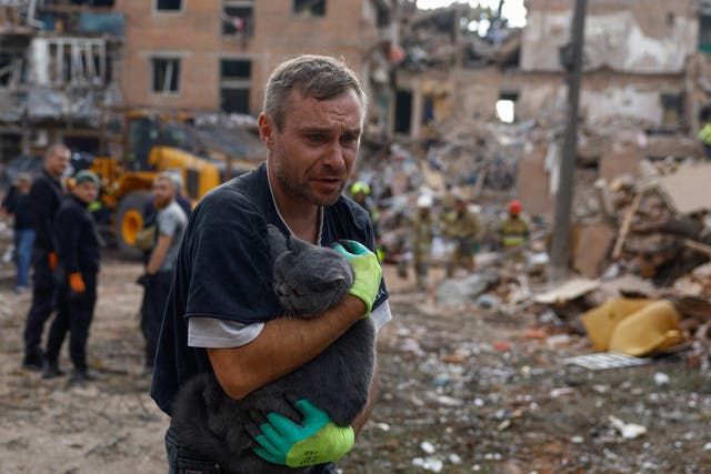 A volunteer carries a cat found at the site of an apartment building hit by a Russian missile strike in the town of Pryluky