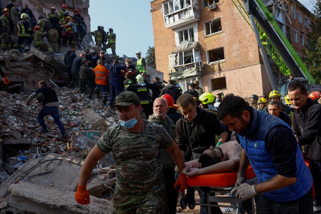 Emergency employees and volunteers carry a resident found under debris in the town of Pryluky