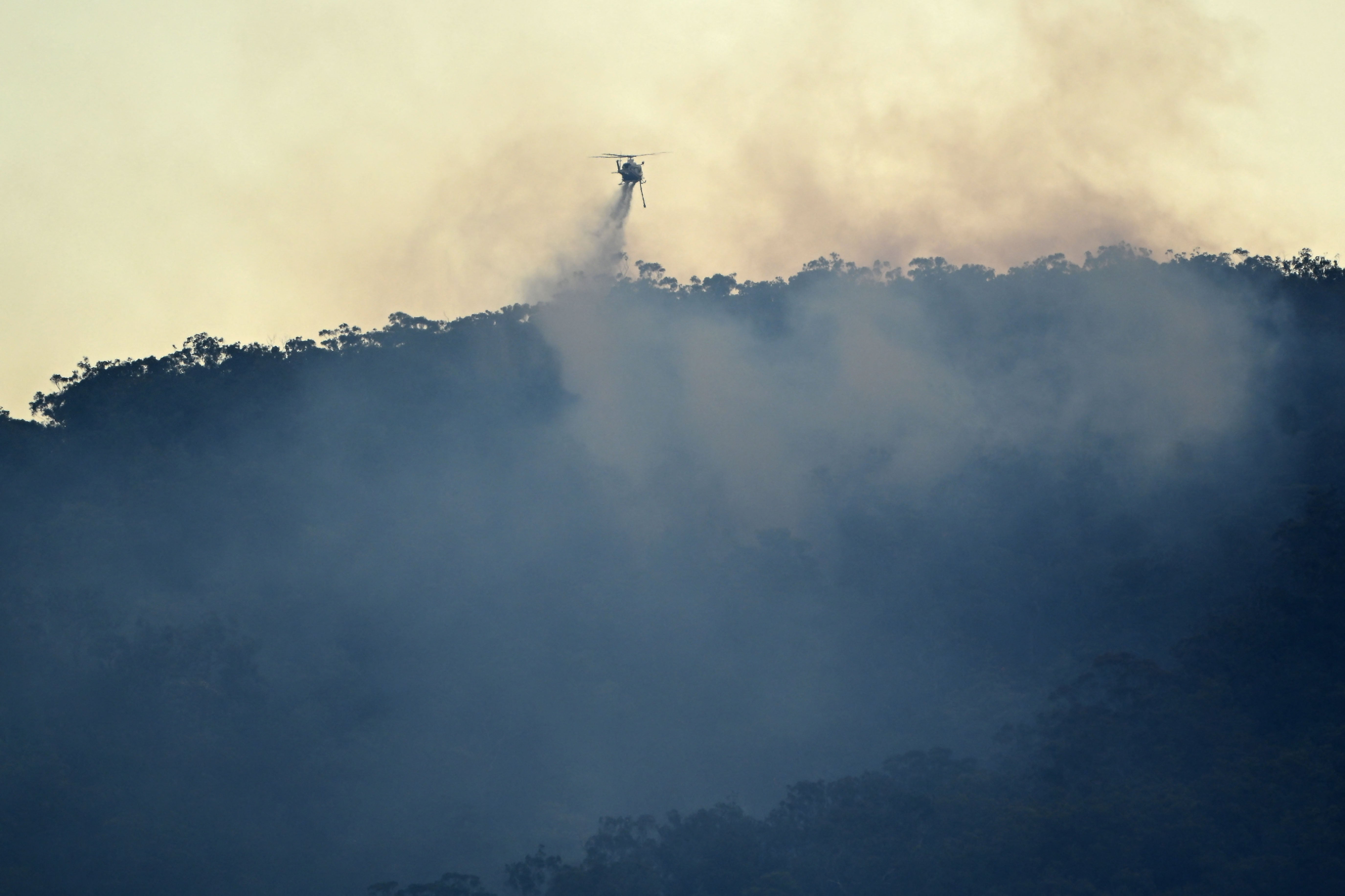 A helicopter drops water on a bushfire on Emu Heights