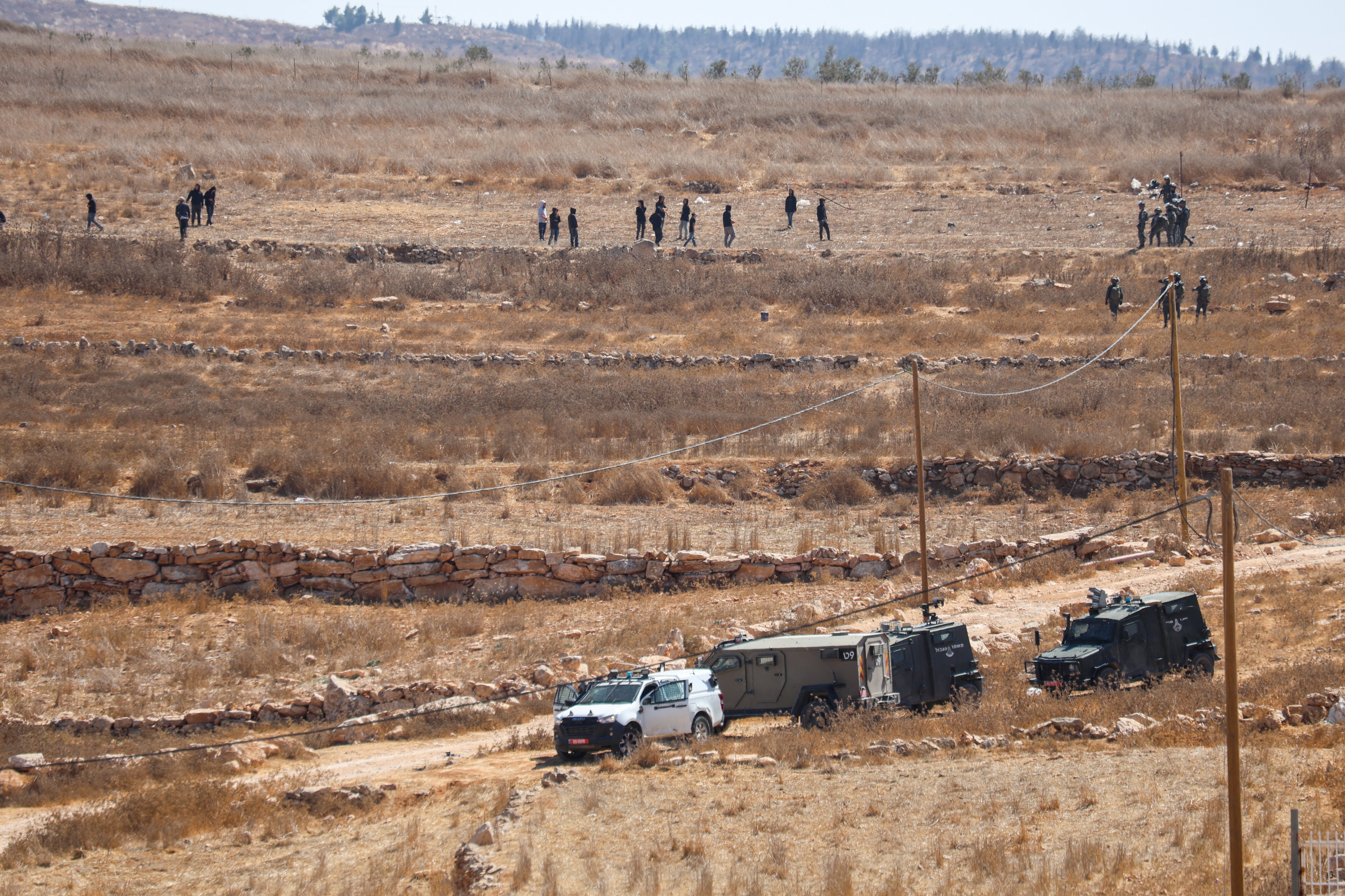 Groups of people are spread across a rocky hillside above several Israeli military vehicles in Wadi al-Rakhim, south of Yatta, occupied West Bank, on October 7, 2026.