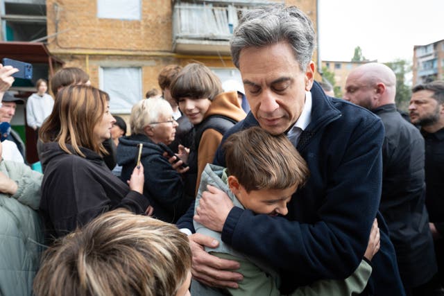 Foreign secretary Ed Miliband embraces a local resident during a visit to the site of a Russian missile strike, which hit a residential area in Pryluky