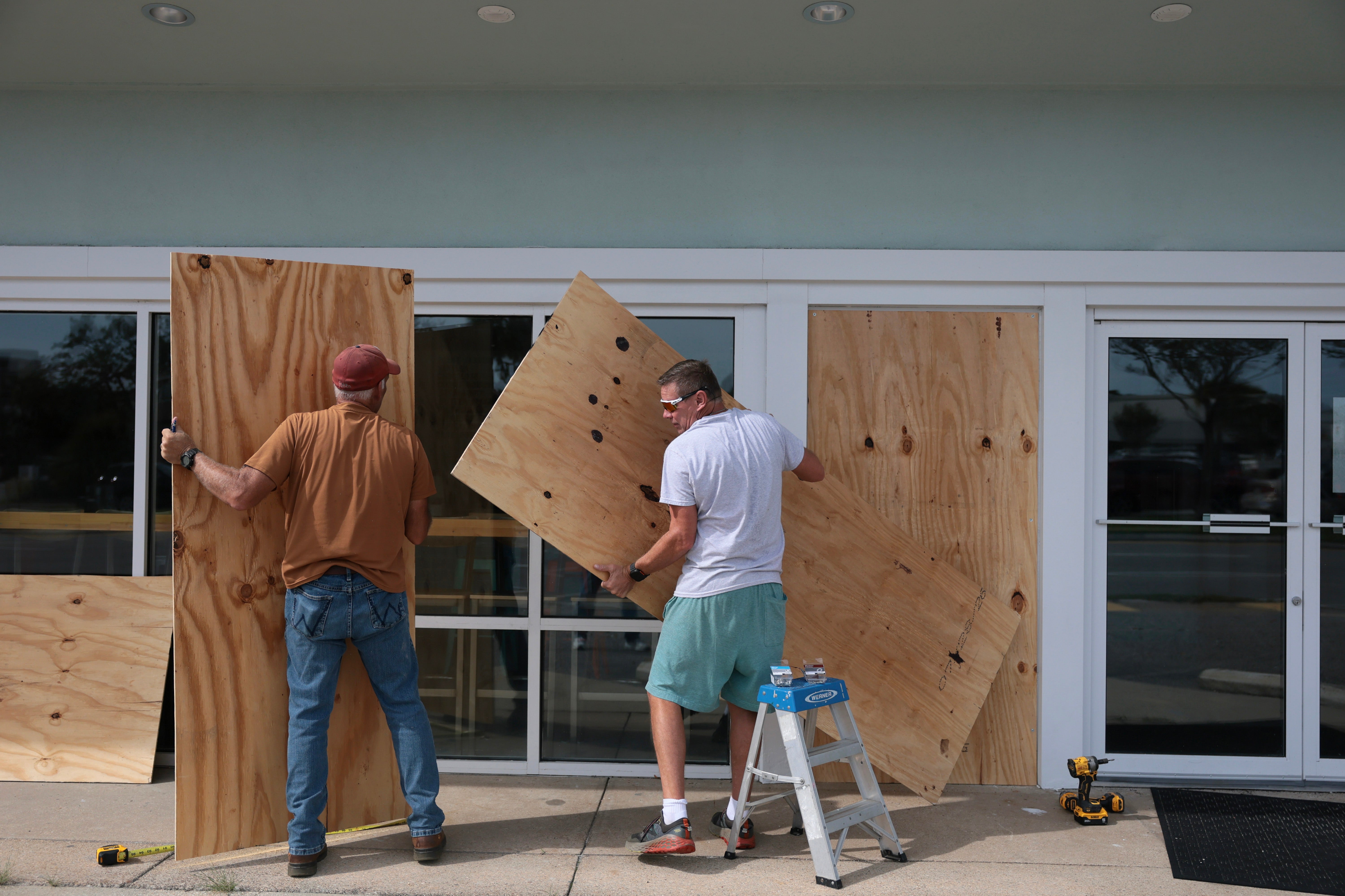 David Schisler and Courtney Head place plywood over the windows of the Islander Ice Cream restaurant as they prepare for the possible arrival of Hurricane Isaias