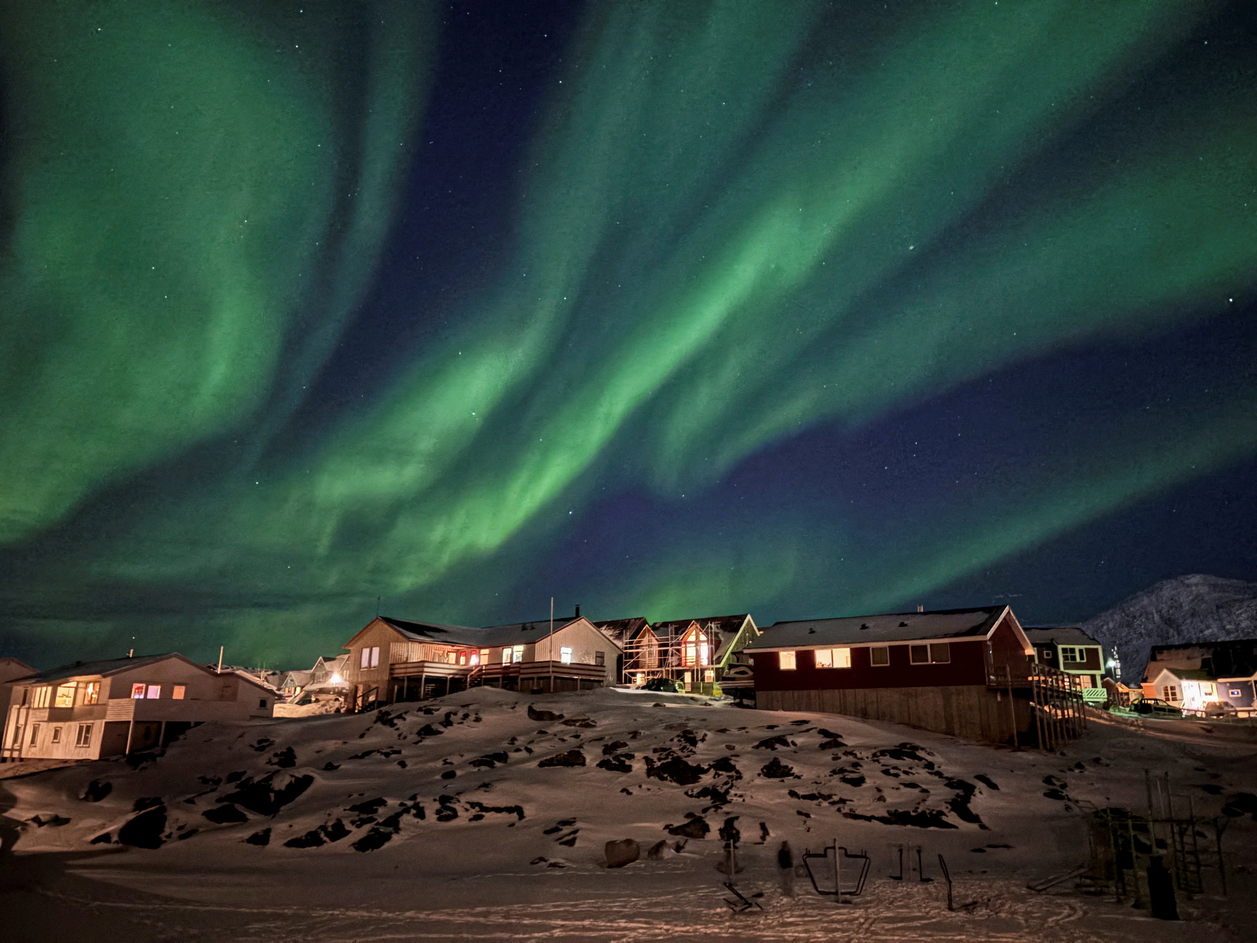 The Aurora Borealis, also known as the Northern Lights, illuminates the sky over houses in Nuuk, Greenland.