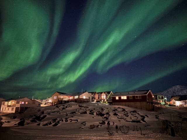 The Aurora Borealis, also known as the Northern Lights, illuminates the sky over houses in Nuuk, Greenland.