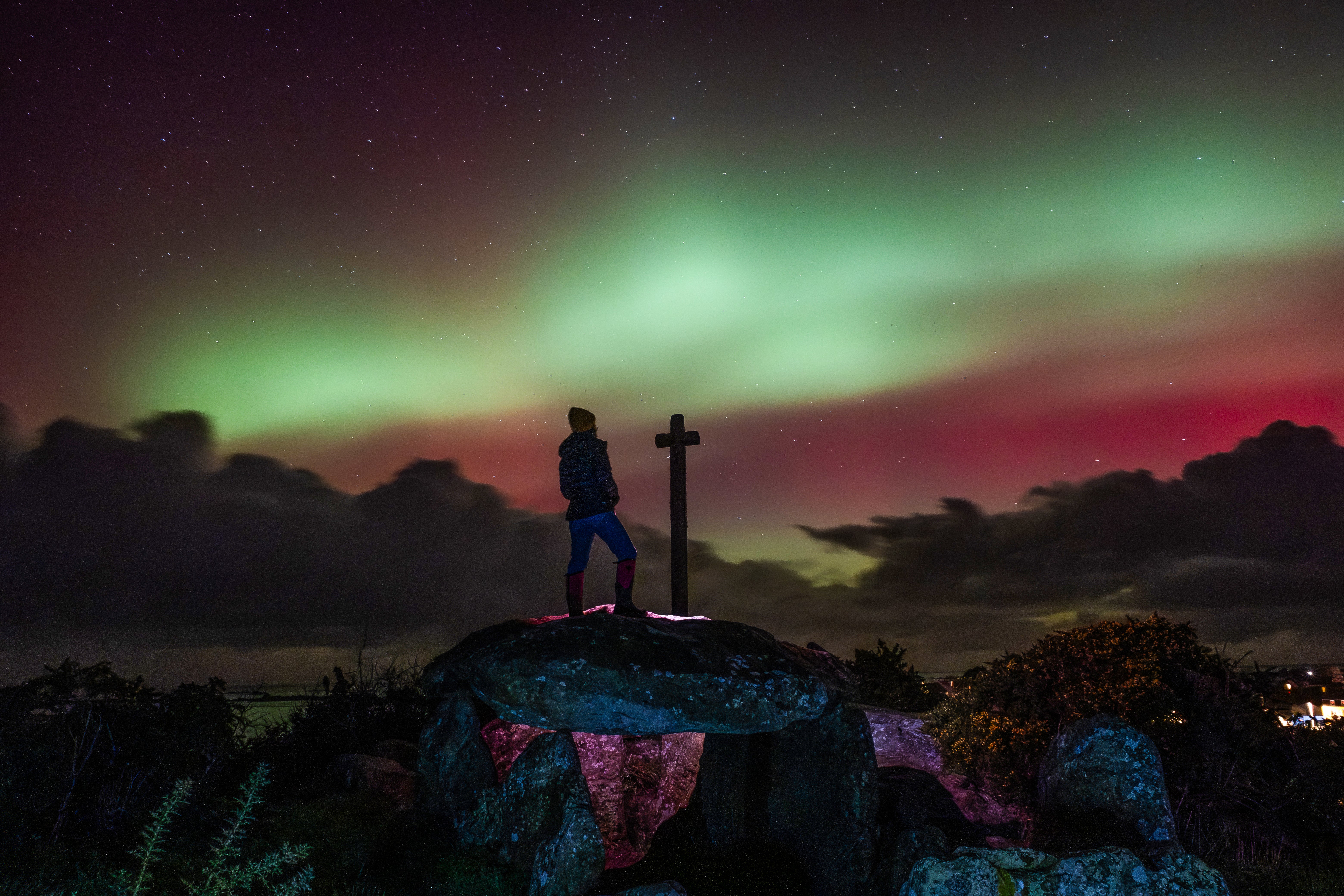 A member of the public looks at Aurora Borealis, or Northern Lights, while standing on a dolmen, an 8000-year-old megalith, following a powerful sunstorm in Guilliguy, western France.