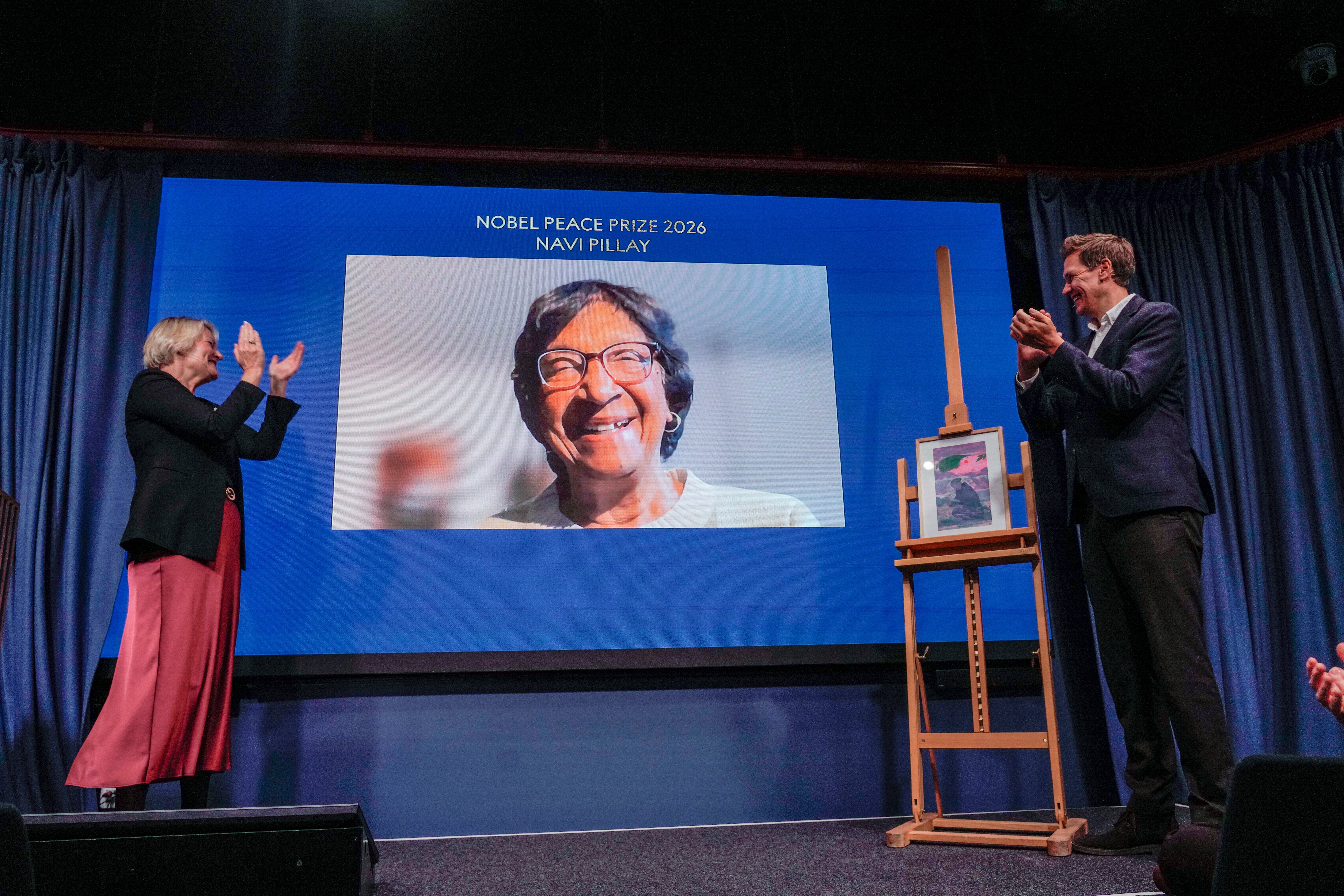 The Director of the Nobel Peace Center, Kjersti Flogstad, left, and the head of the Norwegian Nobel Committee, Jorgen Watne Frydnes, right, applaude as this year's Peace Prize laureate Navanethem Pillay is displayed via video link at the Nobel Peace Center in Oslo, Norway