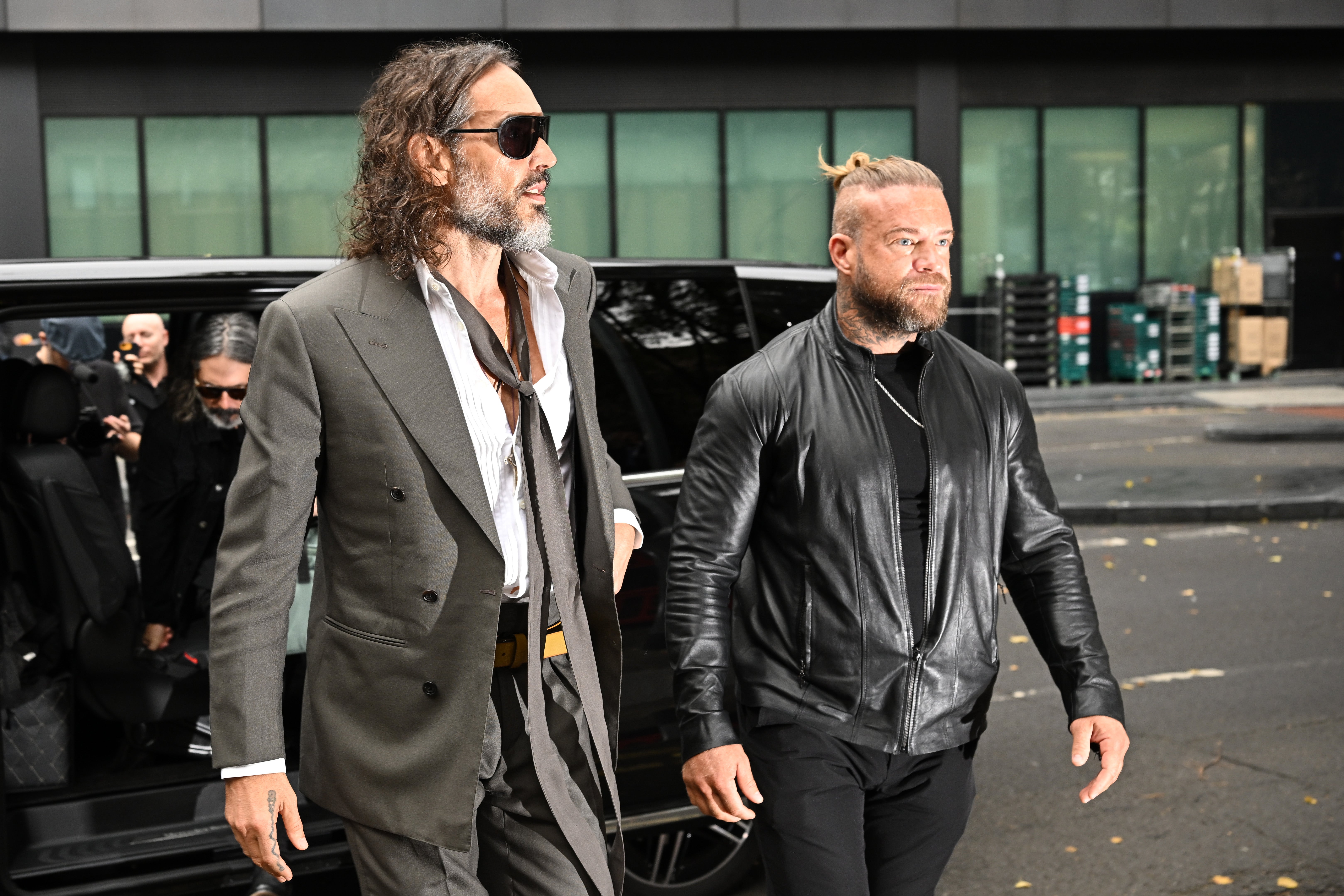 Flanked by his security guard, Brand looked at the cameras pointed at him before taking off his sunglasses as he walked up the steps towards the central London courthouse