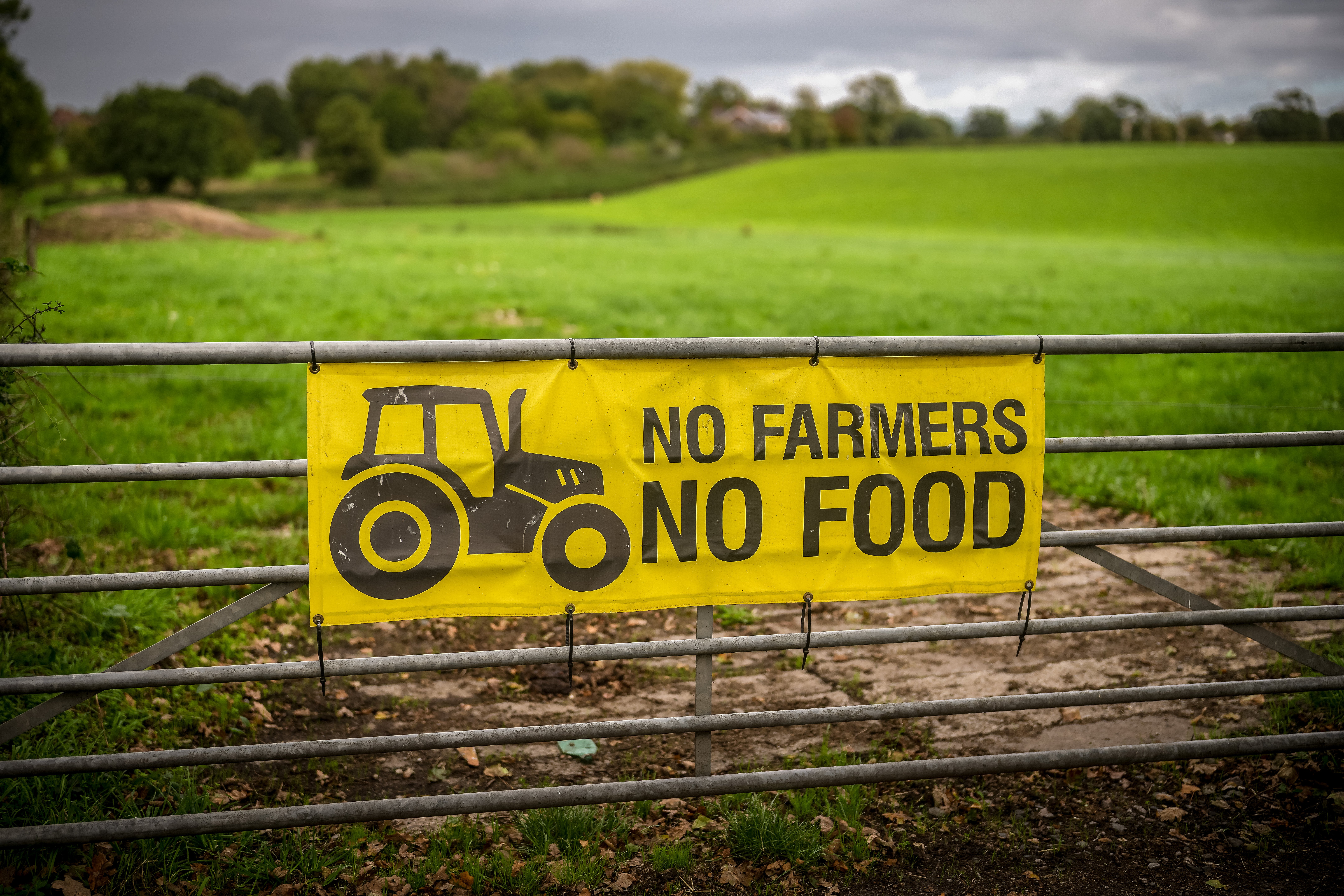 A banner declaring 'No Farmers No Food' hangs from a farm gate in the Cheshire countryside