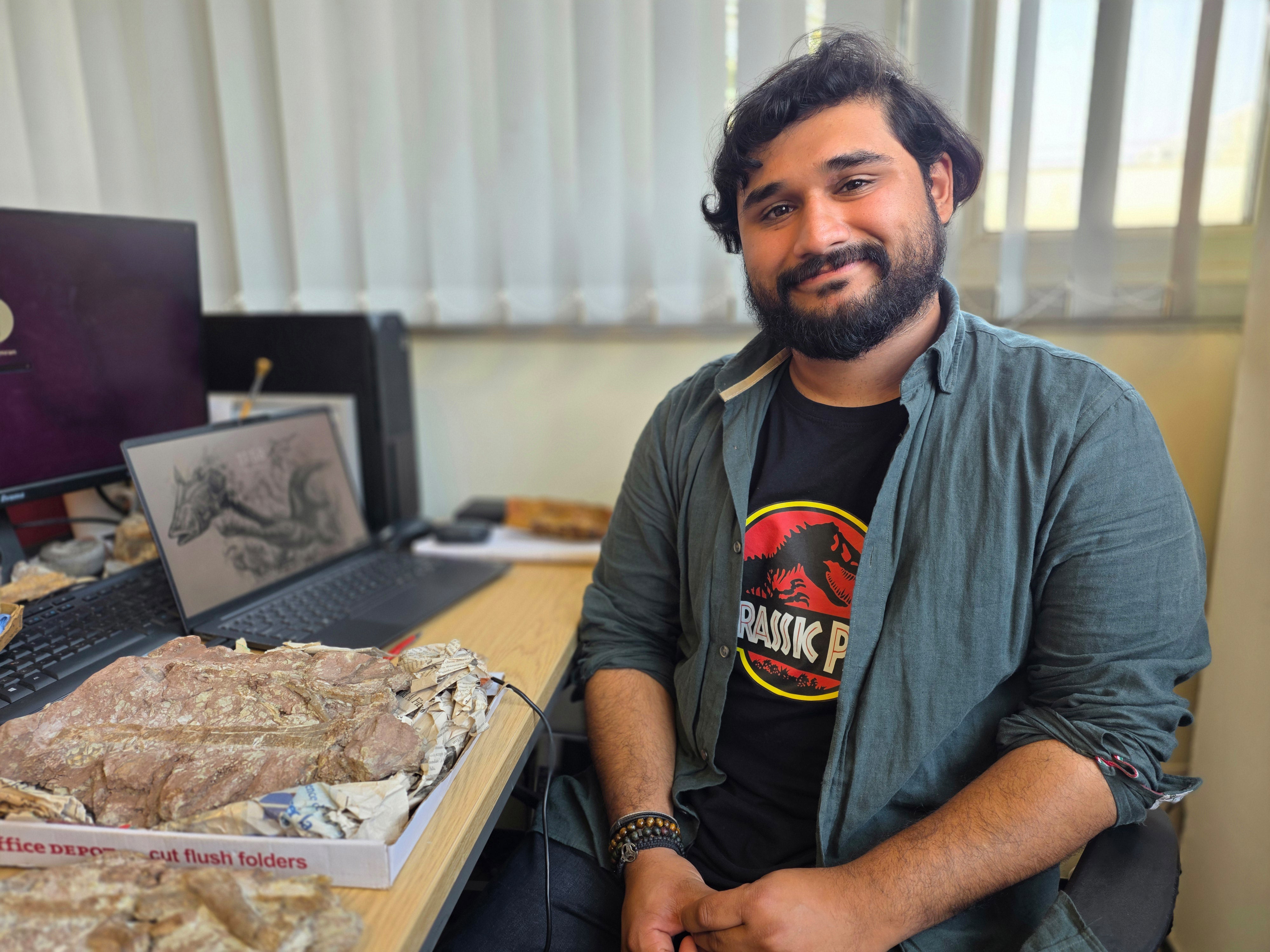 Hamzah Imrah at his desk with the fossil