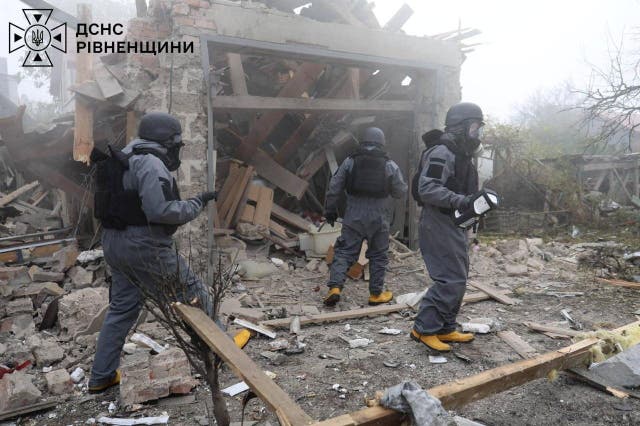 Members of the emergency services work at private houses damaged by a Russian drone strike in Rivne